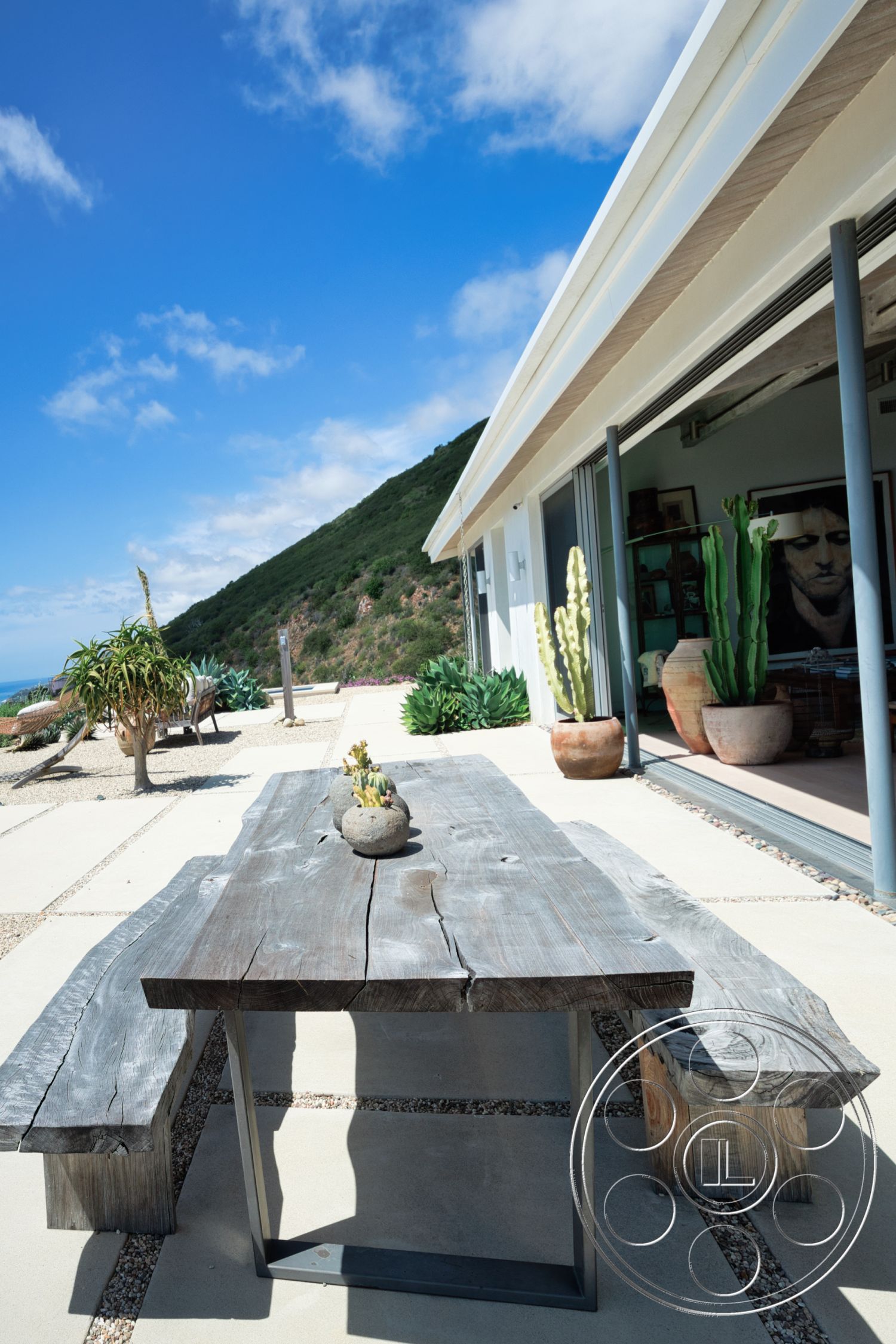 Modern 523 - exterior, modern architecture, large glass sliding doors, minimalist design elements, succulent garden, mountain view setting, concrete patio flooring, wood bench seating, natural landscape integration, potted cactus, weathered wood dining table, decorative gravel border