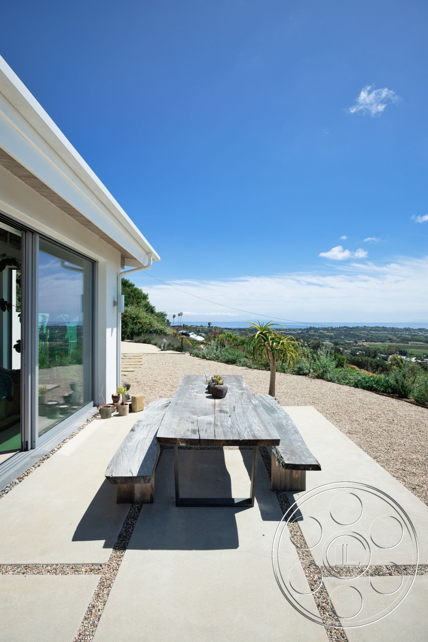Modern 523 - natural light, exterior, minimalist design, floor-to-ceiling windows, outdoor dining area, mountain view, greenery landscaping, gravel landscape, modern house, concrete patio floor, reclaimed wood dining table