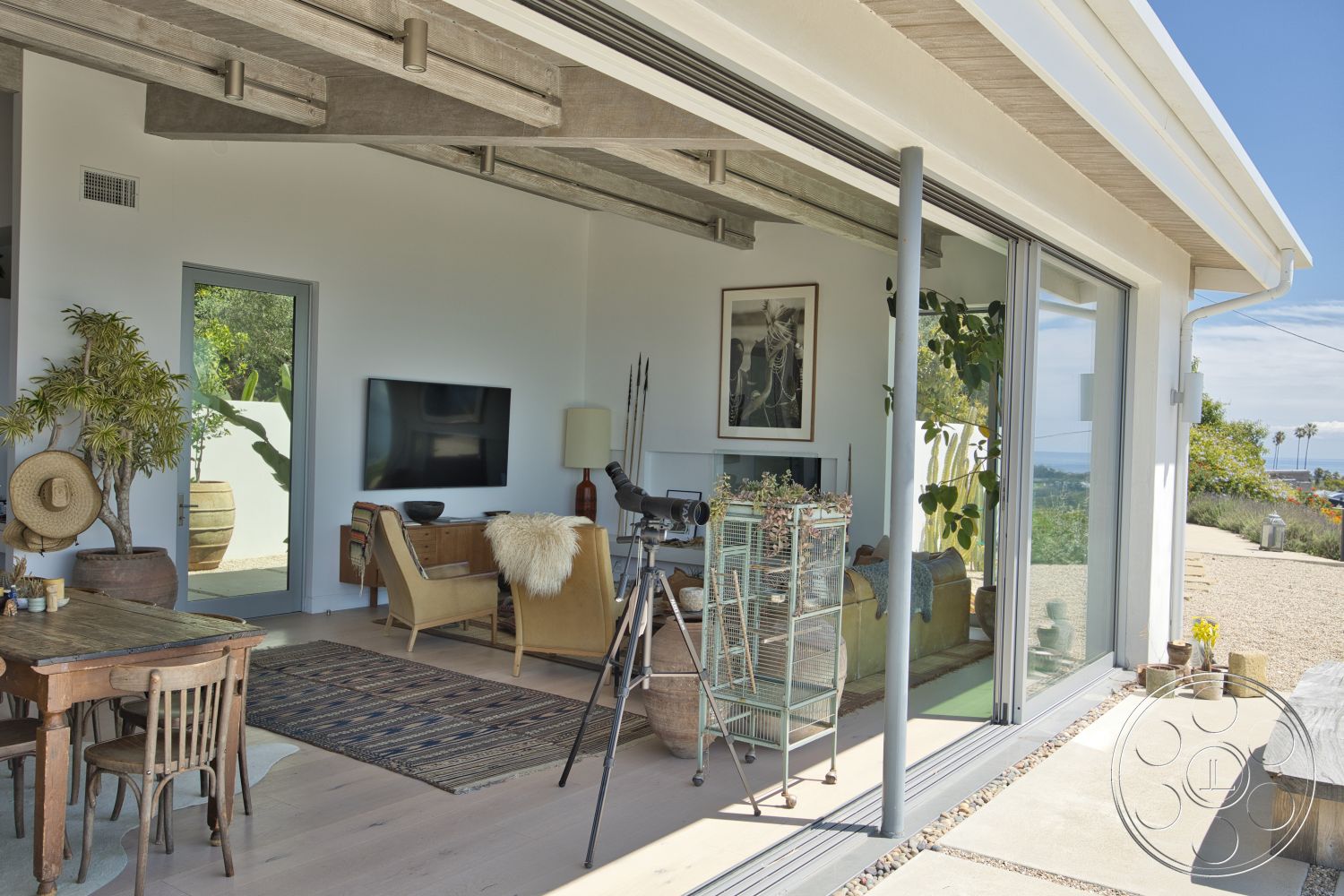 Modern 523 - minimalist decor, neutral color palette, large glass sliding doors, light hardwood flooring, artwork on walls, green indoor plants, woven area rug, modern dining table, stone feature wall, open-plan layout, exposed wood ceiling beams, contemporary lounge chair