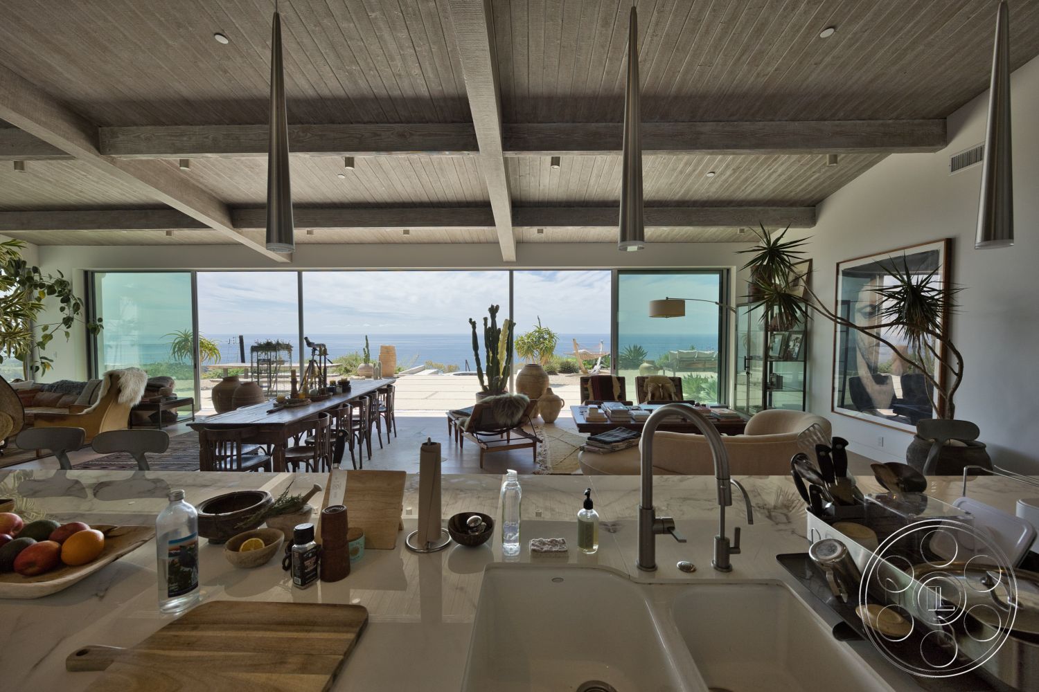 Modern 523 - exterior, open floor plan, modern pendant lighting, glass sliding doors, concrete patio, floor-to-ceiling windows, ocean view, textured plaster walls, large potted plants, stylish lounge chairs, wood beam ceiling, dining area with wooden table, integrated kitchen island with marble countertop, natural wood dining chairs, modern art wall frames