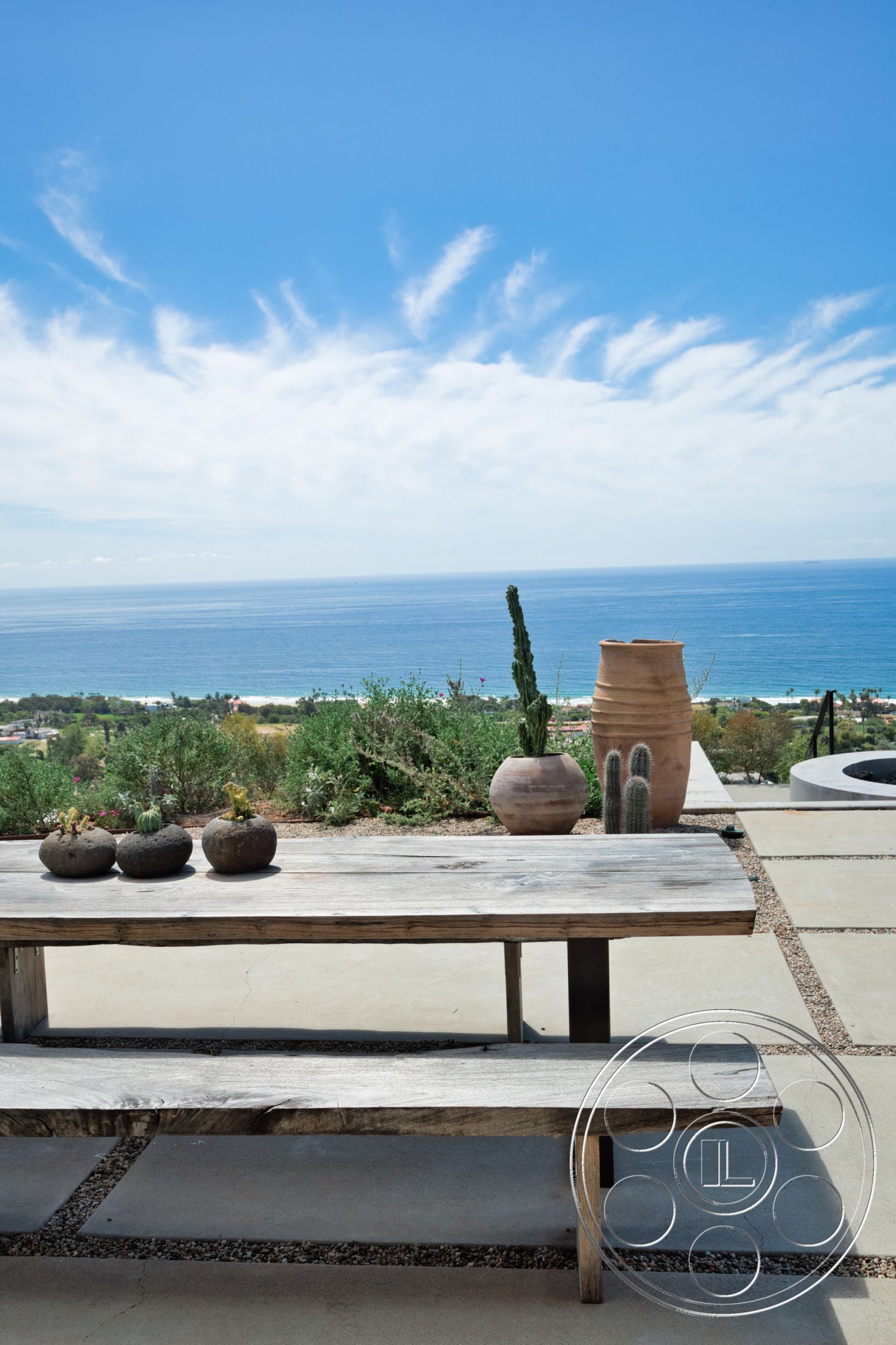 Modern 523 - exterior, wood dining table, ocean view, blue sky, ceramic planters, tropical vegetation, natural wood bench, concrete patio flooring, desert landscape setting, rustic decorative stones