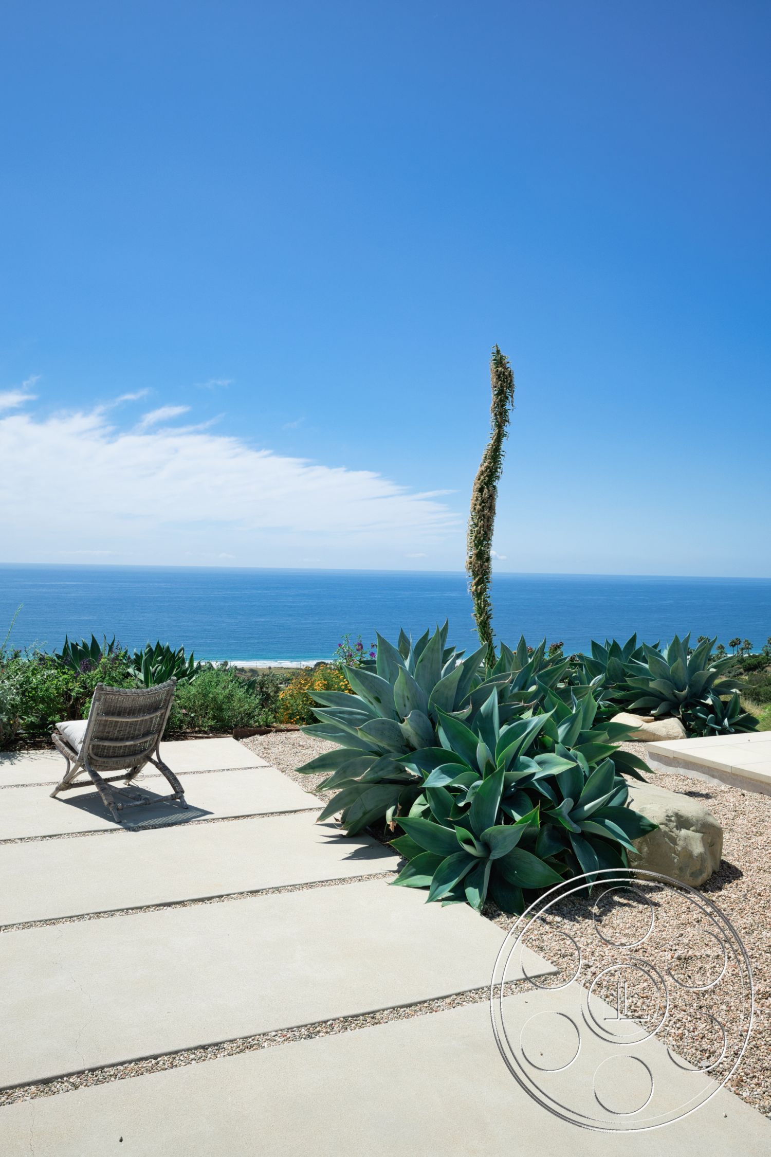 Modern 523 - exterior, outdoor seating area, gravel landscaping, clear blue sky, stone accents, concrete patio slabs, ocean view setting, large succulent plants, tropical garden design