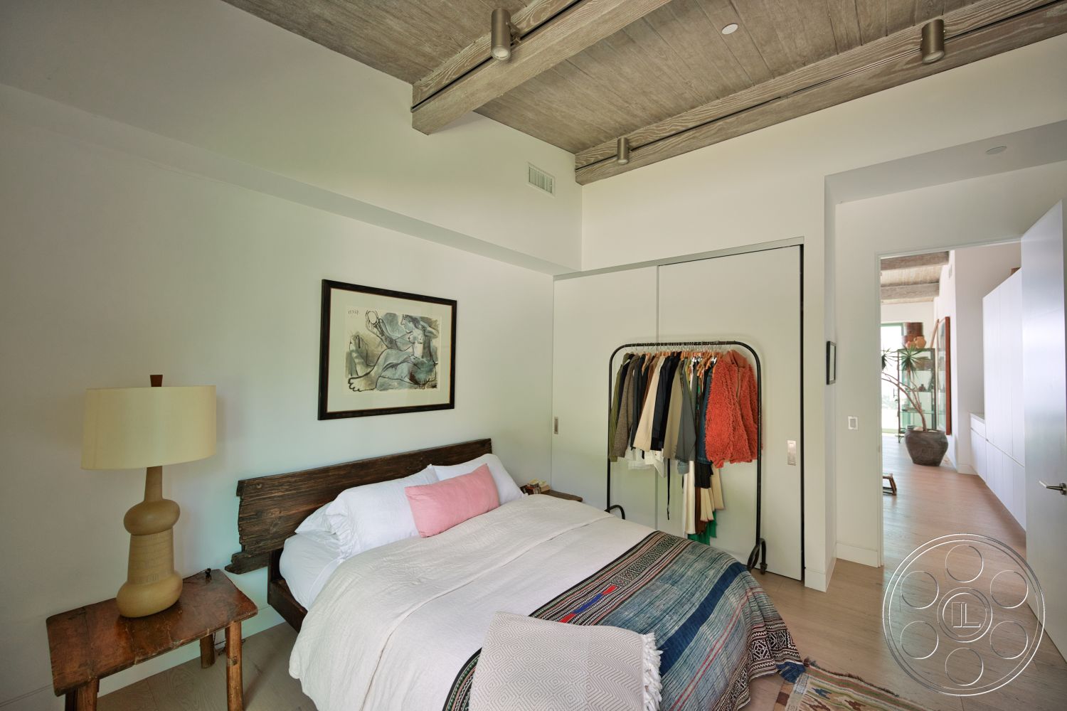 Modern 523 - neutral color palette, natural light, decorative wall art, textured plaster walls, exposed concrete ceiling, open doorway, wood bed frame, hardwood bedroom floors, minimalist lamp, custom closet system, colorful textile blanket