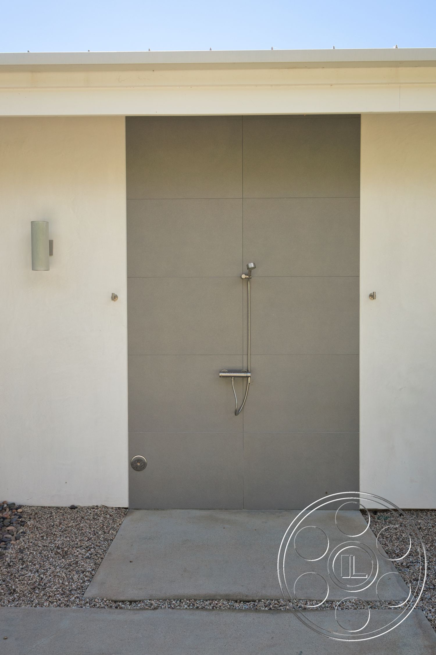 Modern 523 - exterior, concrete wall, modern architectural style, gravel landscaping, desert setting, smooth concrete entryway, gray tile door, minimalist door design, stainless steel door handle, missing traditional door, floor drainage