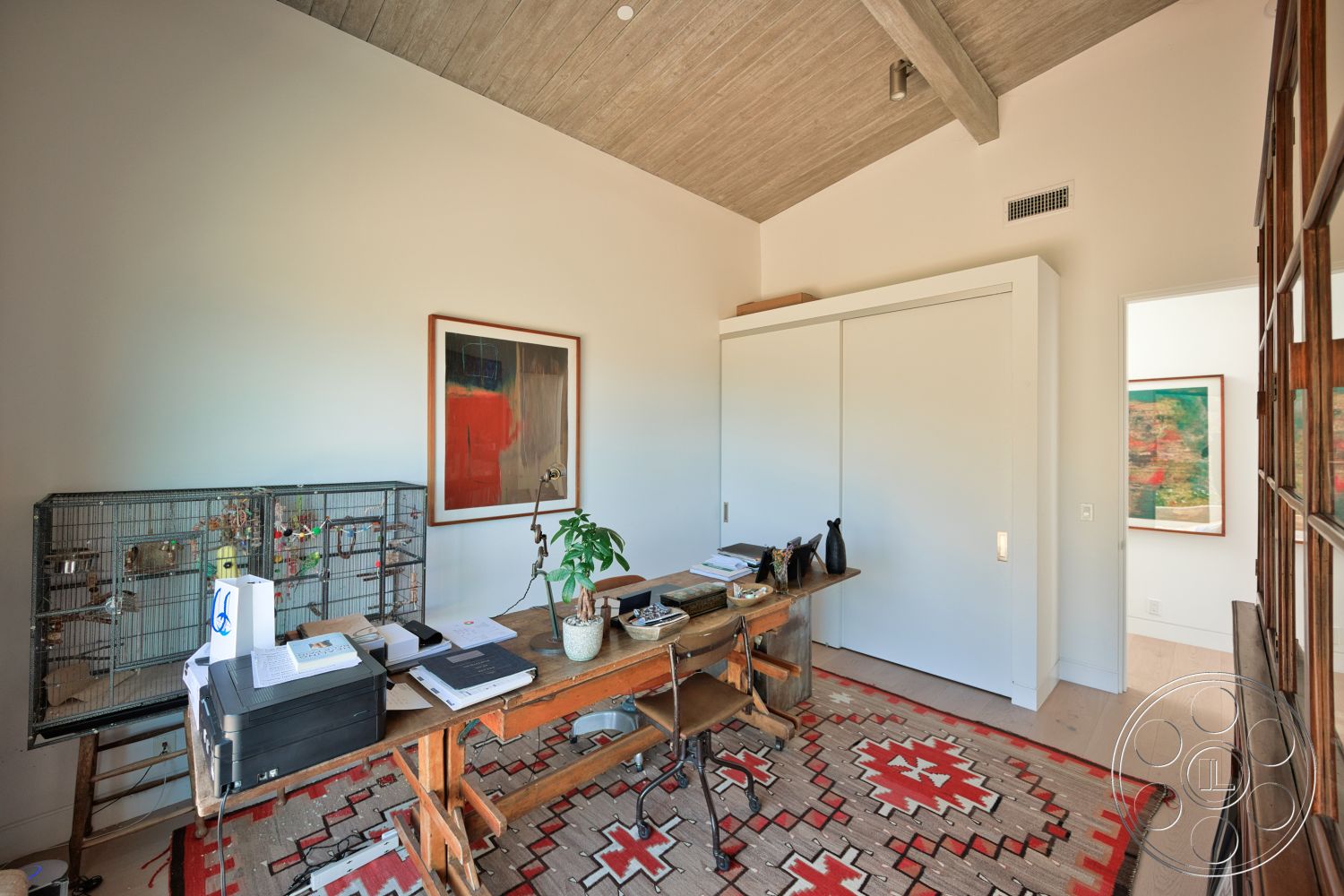 Modern 523 - hardwood flooring, wooden desk, textured plaster walls, traditional patterned area rug, wood beam ceiling, window with view to hallway, modern painting wall art, minimalist sliding closet doors, metal birdcage, natural plant decoration