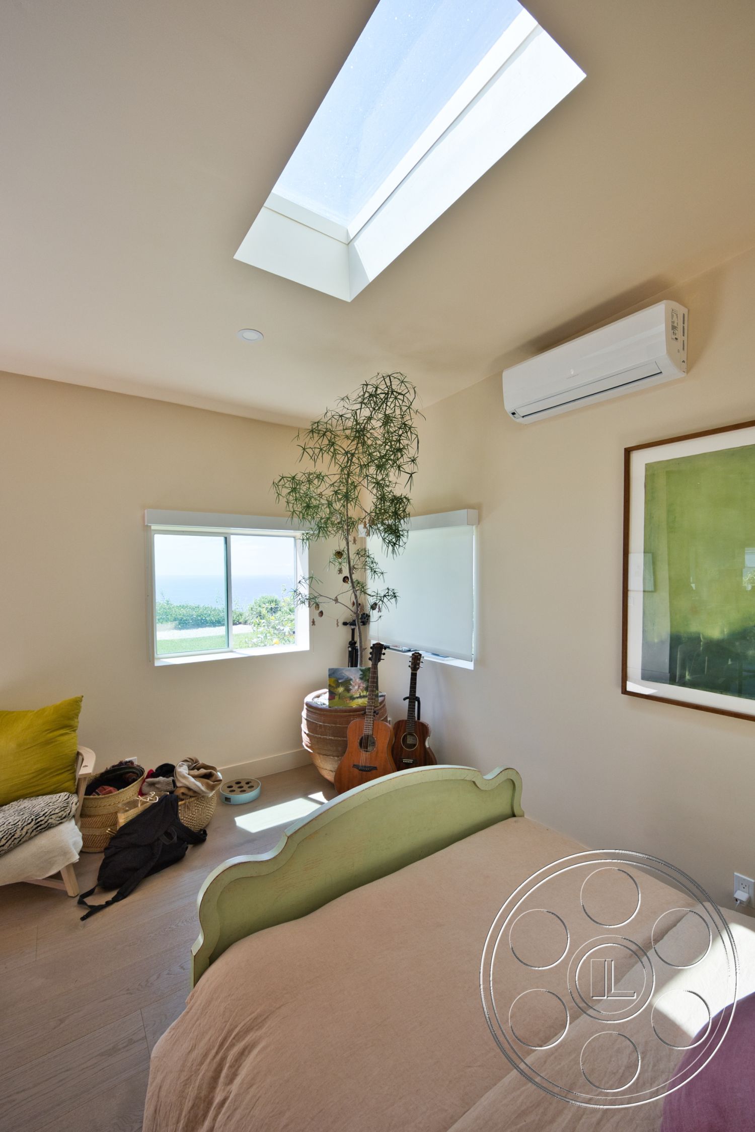 Modern 523 - natural wood flooring, floor-to-ceiling windows, skylight ceiling, light beige painted walls, acoustic guitar display, minimalist bedroom design, green accent wall art, green upholstered bed frame, indoor plant with decorative pot, seating area with woven basket