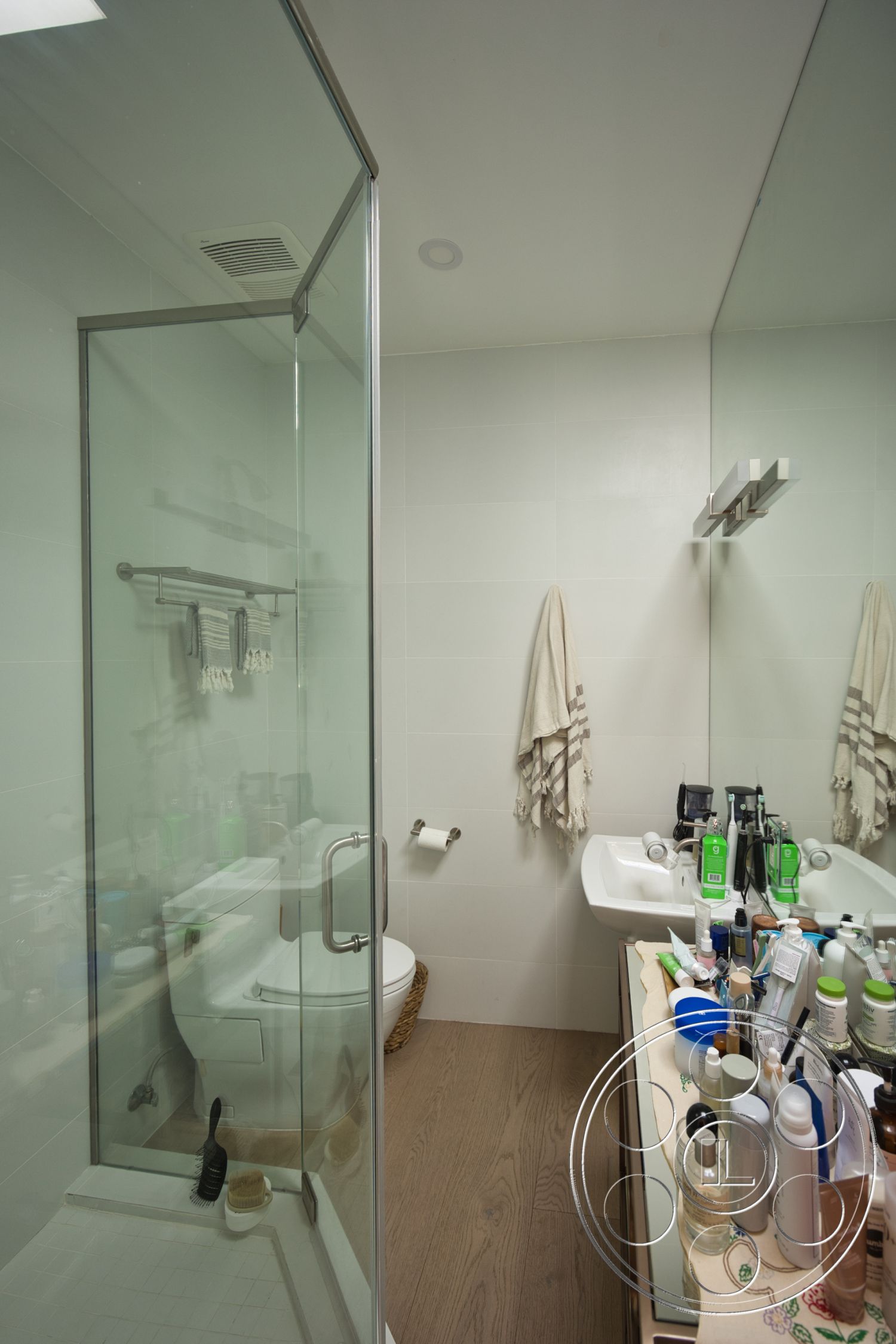 Modern 523 - white toilet, dual sink vanity, glass shower doors, modern bathroom design, tile bathroom walls, wood-colored bathroom flooring, mirror with integrated lighting, towel bar