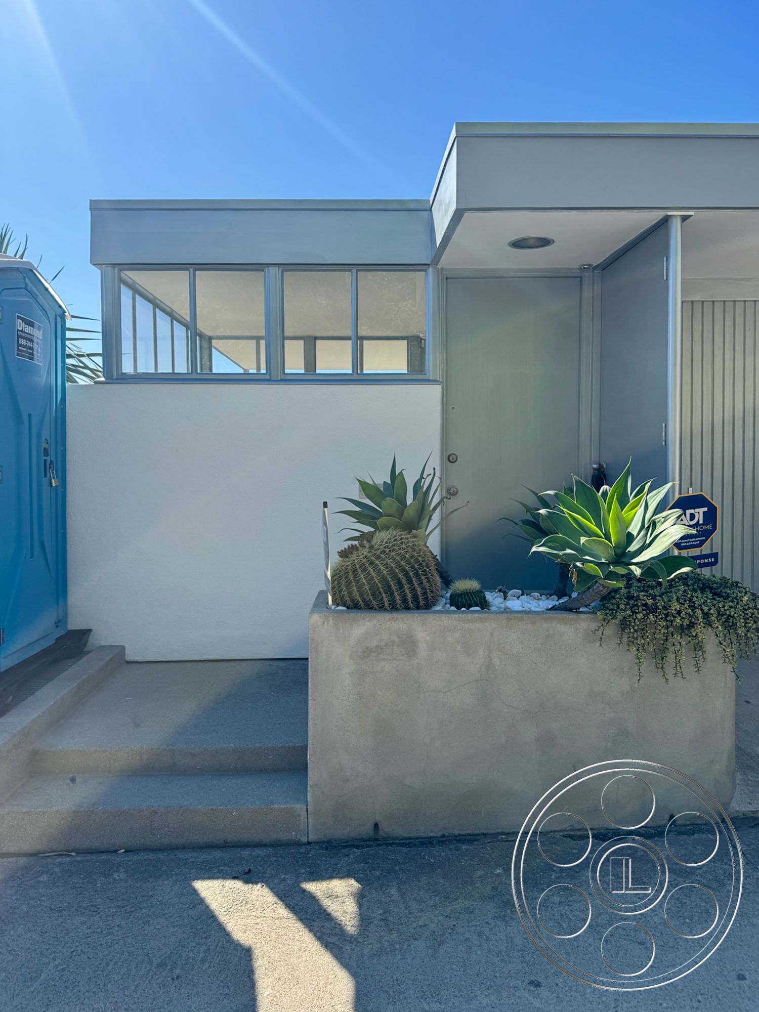 The Kun House - exterior, concrete steps, desert landscaping, metal door, flat roof design, stucco wall finish, modernist architectural style, glass window panels, succulent planter box, direct sunlight exposure