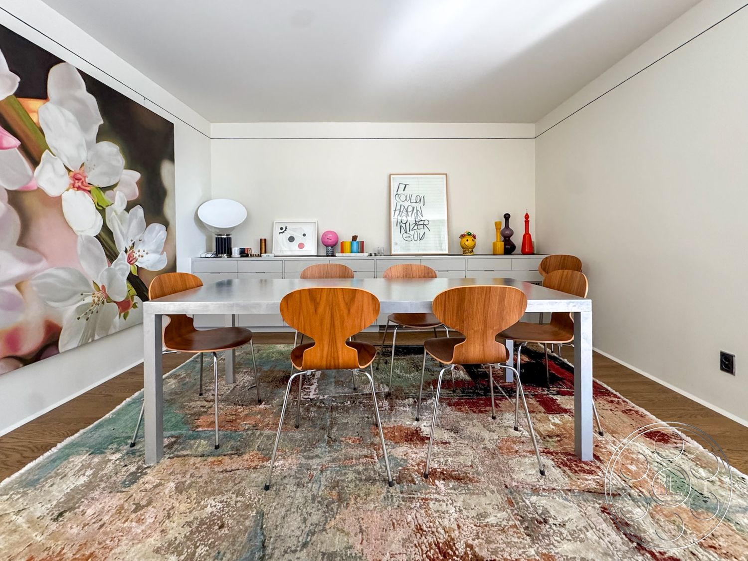 The Kun House - hardwood flooring, textured area rug, modern design elements, rectangular dining table, wooden dining chairs, white painted walls, exposed wood ceiling, framed artwork on wall, stainless steel table legs, large floral wall art, minimalist credenza, decorative vases on display