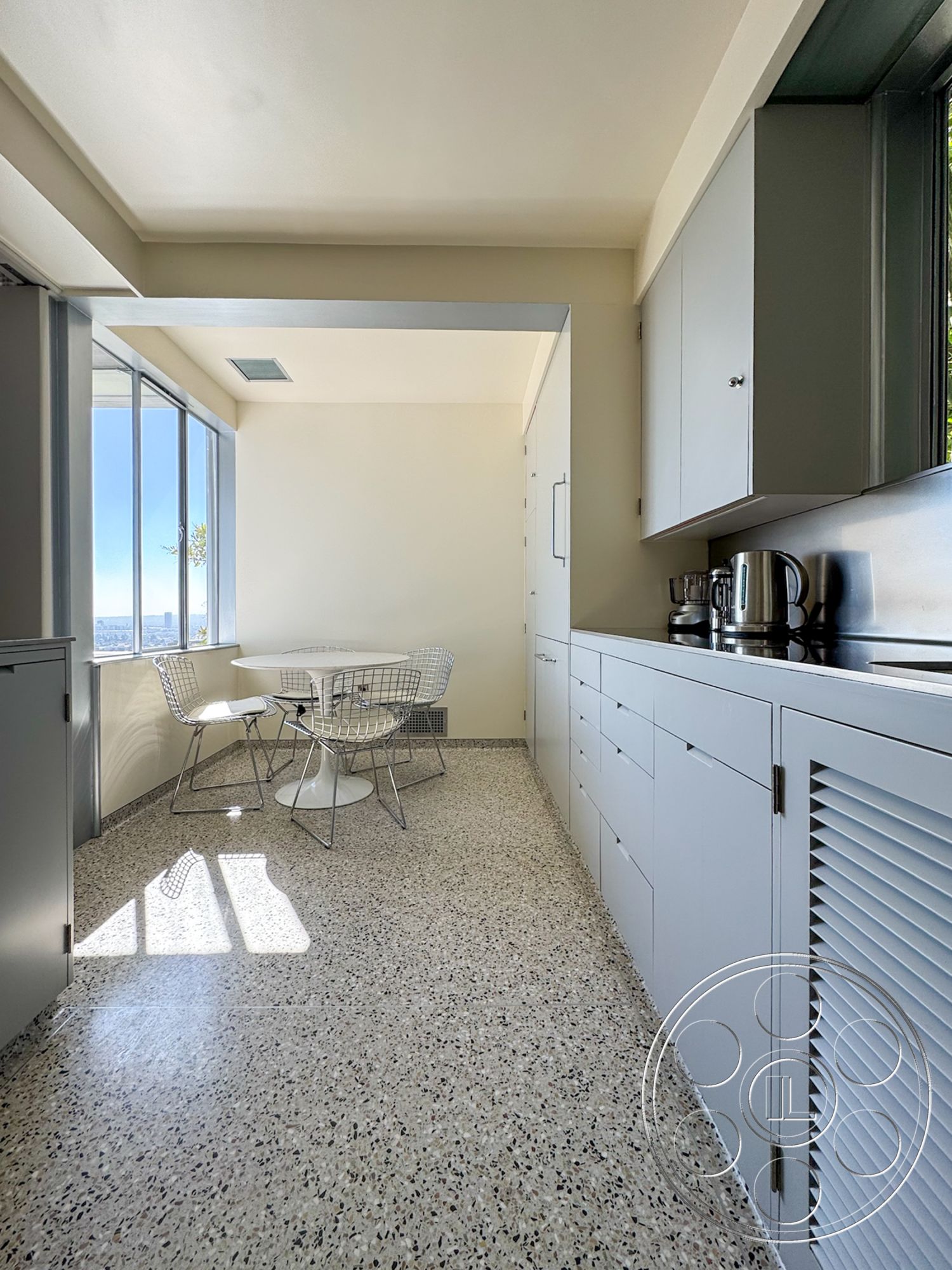 The Kun House - modern kitchen, minimalist design, terrazzo flooring, floor-to-ceiling windows, light grey cabinetry, open layout kitchen, white round dining table, wire mesh dining chairs