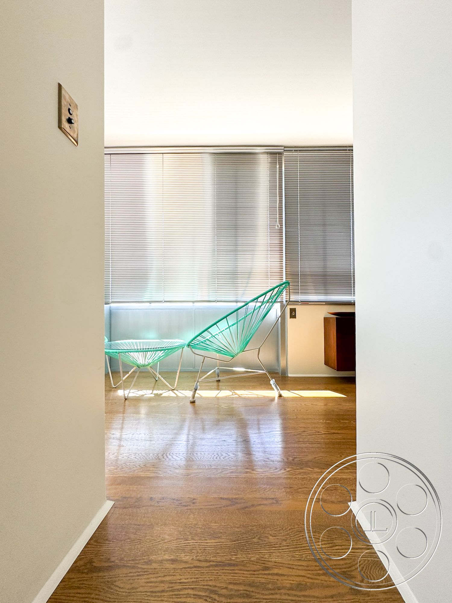 The Kun House - natural light, hardwood flooring, minimalist design, contemporary furniture, open space layout, mid-century modern style, white painted walls, metal window blinds, green wire accent chairs
