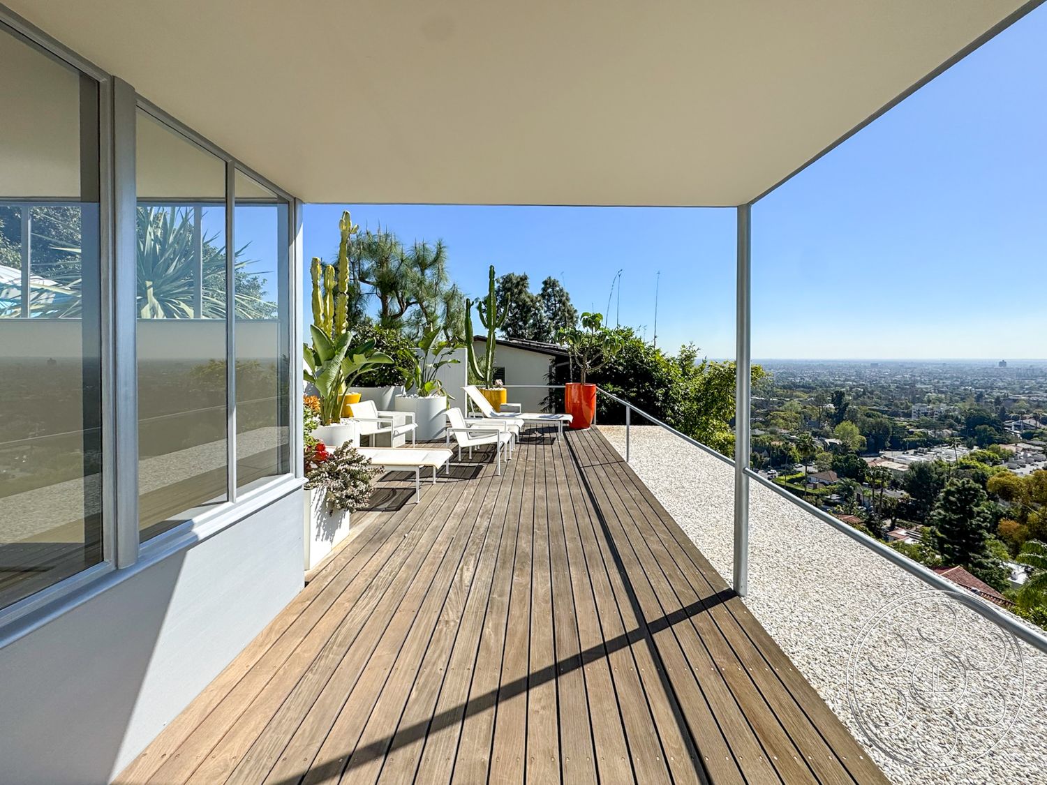 The Kun House - exterior, metal railing, urban skyline view, cactus garden, glass sliding door, wood deck flooring, concrete patio edge, plant containers, floating roof overhang