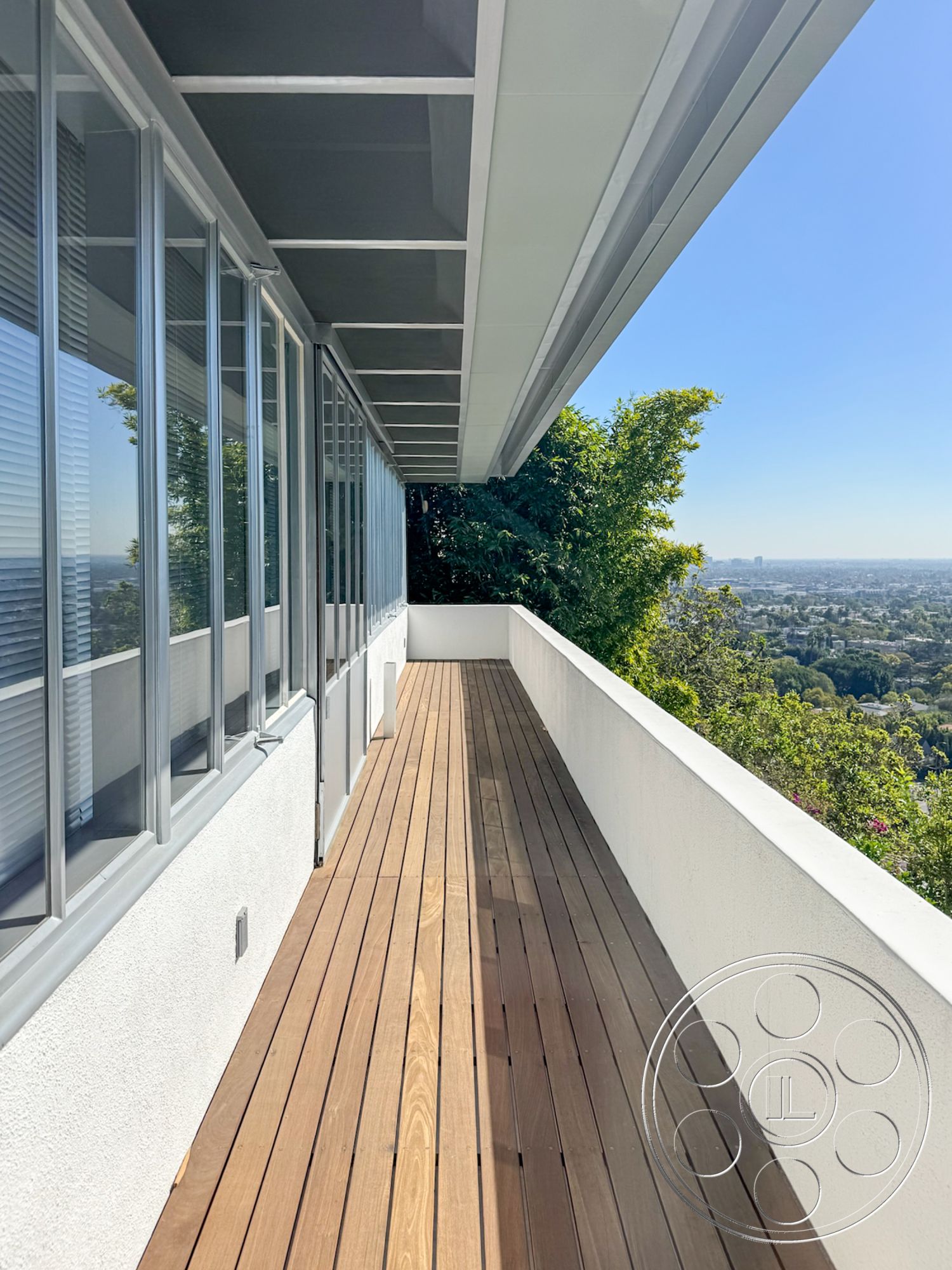 The Kun House - exterior, floor-to-ceiling windows, modern architectural style, city skyline view, flat roof design, glass window frames, metal roof overhang, wood balcony flooring, concrete balcony walls