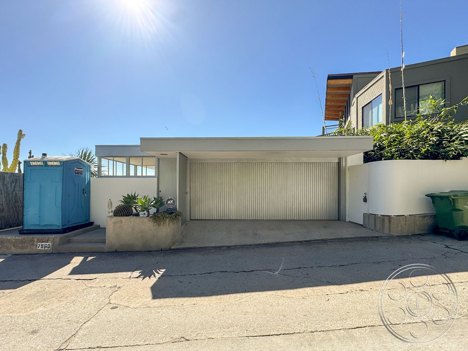The Kun House - exterior, minimalist design, glass windows, modern architectural style, landscaped planters, concrete driveway, horizontal wood paneling, metal garage door, plant accent features, staircase landing