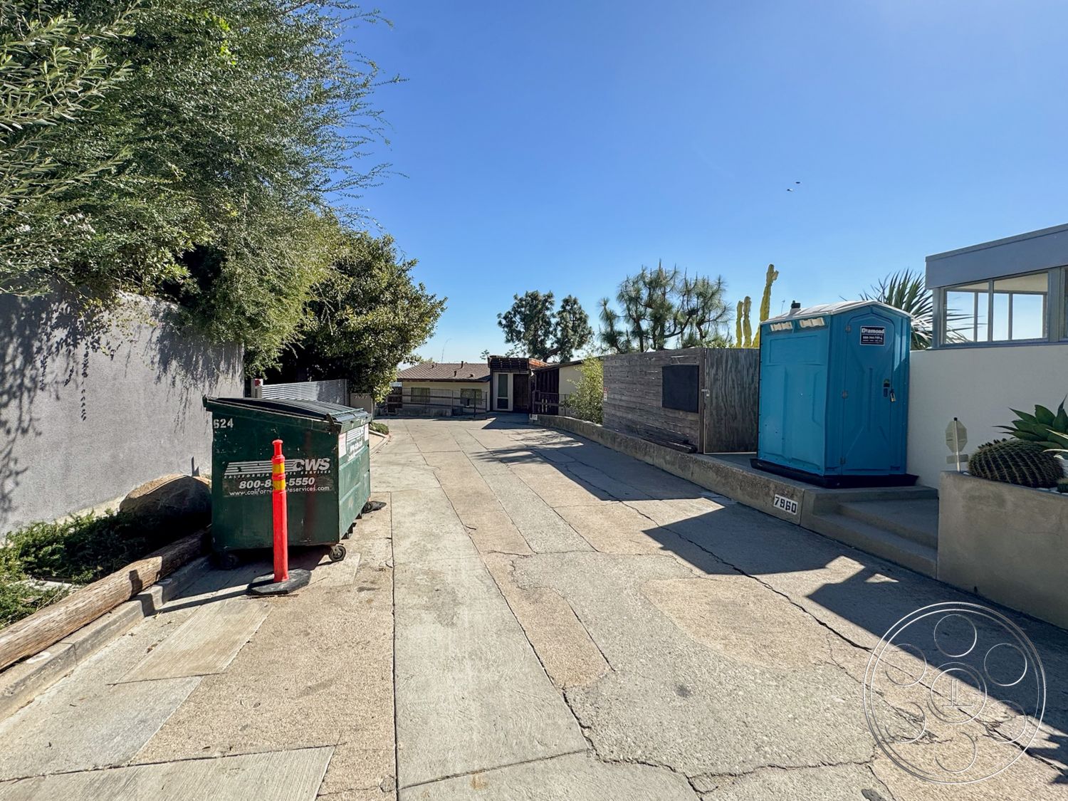 The Kun House - exterior, landscaped garden, concrete pavement, urban setting, concrete driveway, gray stucco wall, cactus garden, portable restroom, wood fence, green waste dumpster