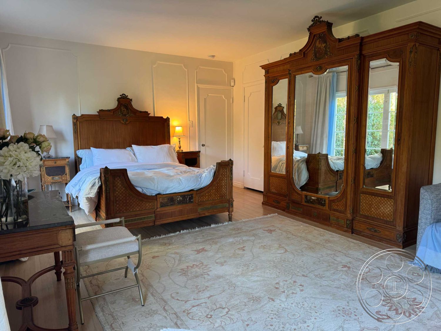 Medit 156 - decorative bedside lamp, ornate wooden bed frame, luxurious bedding, elegant area rug, cozy bedroom setting, hardwood bedroom floors, white painted walls, large windows with natural light, detailed wood paneling, mirrored wardrobe cabinet, crowned ceiling molding, detailed furniture craftsmanship, classic French style decor