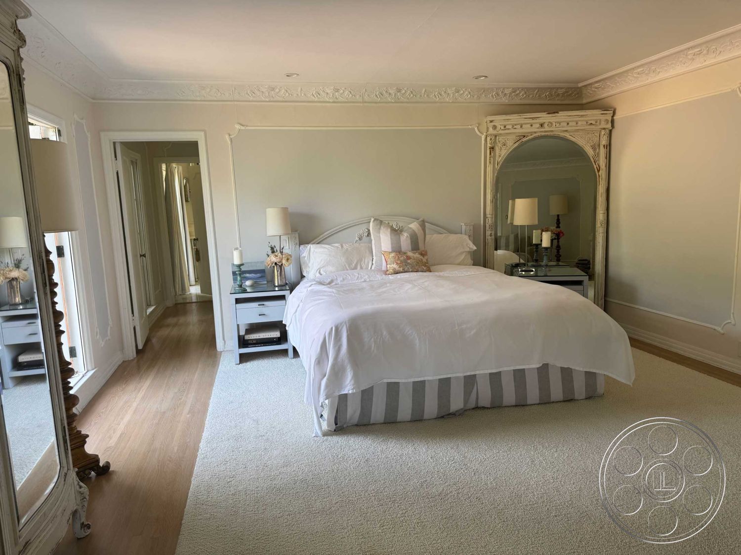 Medit 156 - neutral color palette, spacious layout, decorative crown molding, soft lighting fixtures, wooden bedside tables, ornate ceiling details, queen-size bed, laminate wood flooring, carpet bedroom flooring, walls with textured plaster finish, mirrored accent furniture, striped bed skirt, large floor mirror, elegant bedroom decor