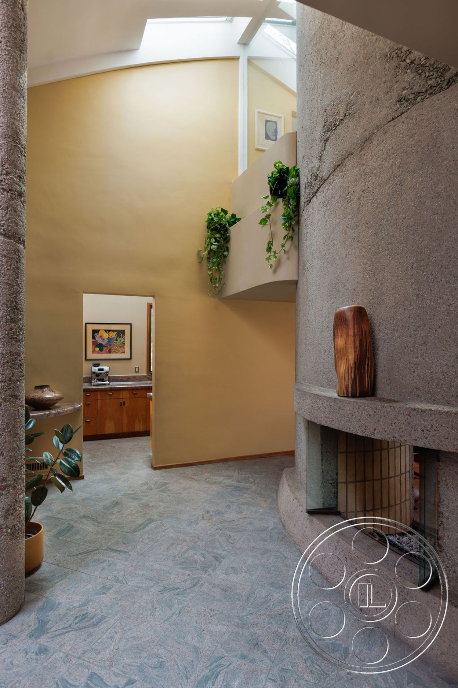 Mid-Century Exotic - natural wood accents, ceramic tile flooring, exposed concrete walls, modern architectural style, textured plaster walls, artwork on display, rounded wall, indoor plant decor, curved staircase, light beige wall treatment, laminate kitchen cabinetry, grey stone fireplace, floor-to-ceiling fireplace glass, natural lighting from skylight