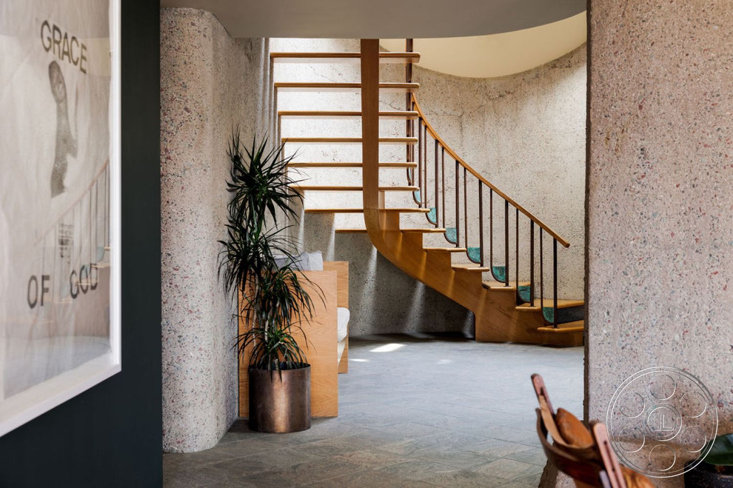 Mid-Century Exotic - minimalist decor, neutral color palette, open concept layout, polished stone flooring, contemporary interior design, indoor potted plants, exposed aggregate concrete walls, textured plaster wall details, wooden spiral staircase, rounded architectural forms, glass wall artwork, natural light from overhead, half-landing staircase, light wood handrails