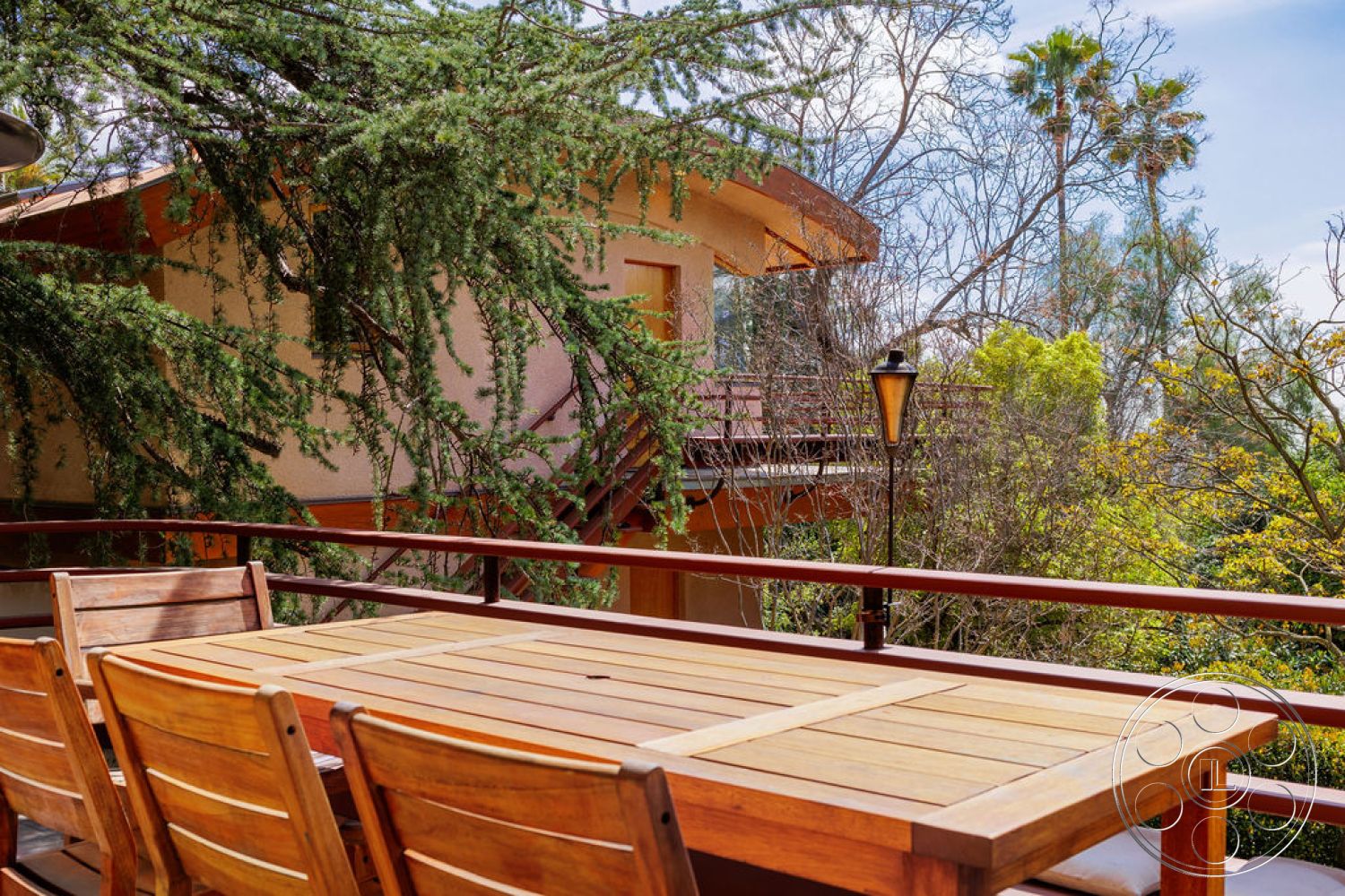 Mid-Century Exotic - exterior, lush greenery, wooden chairs, natural vegetation, tall trees, outdoor lighting fixtures, overhanging eaves, textured stucco walls, landscaped garden setting, wood deck patio, balcony railing, teak dining table