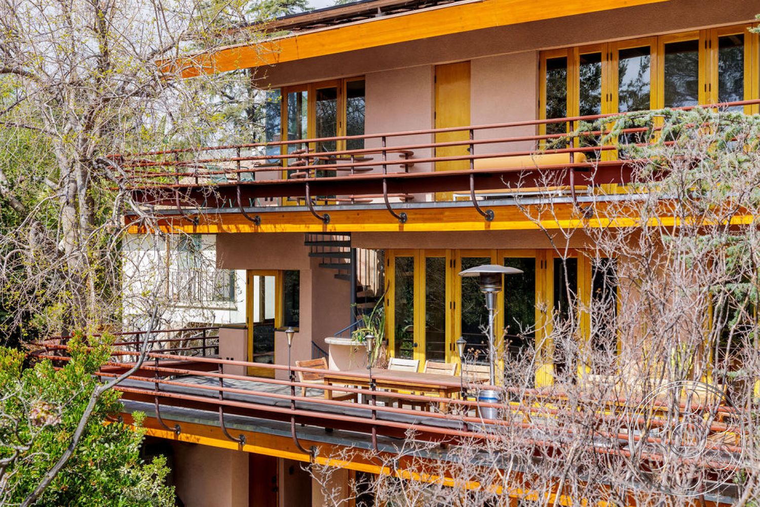 Mid-Century Exotic - exterior, flat roof, large glass windows, exposed concrete walls, modern architectural style, wood ceiling beams, natural wood siding, stone steps, two-story home, steel spiral staircase, wood balcony railing, terrace with outdoor seating, designed landscape with greenery, horizontal redwood slats