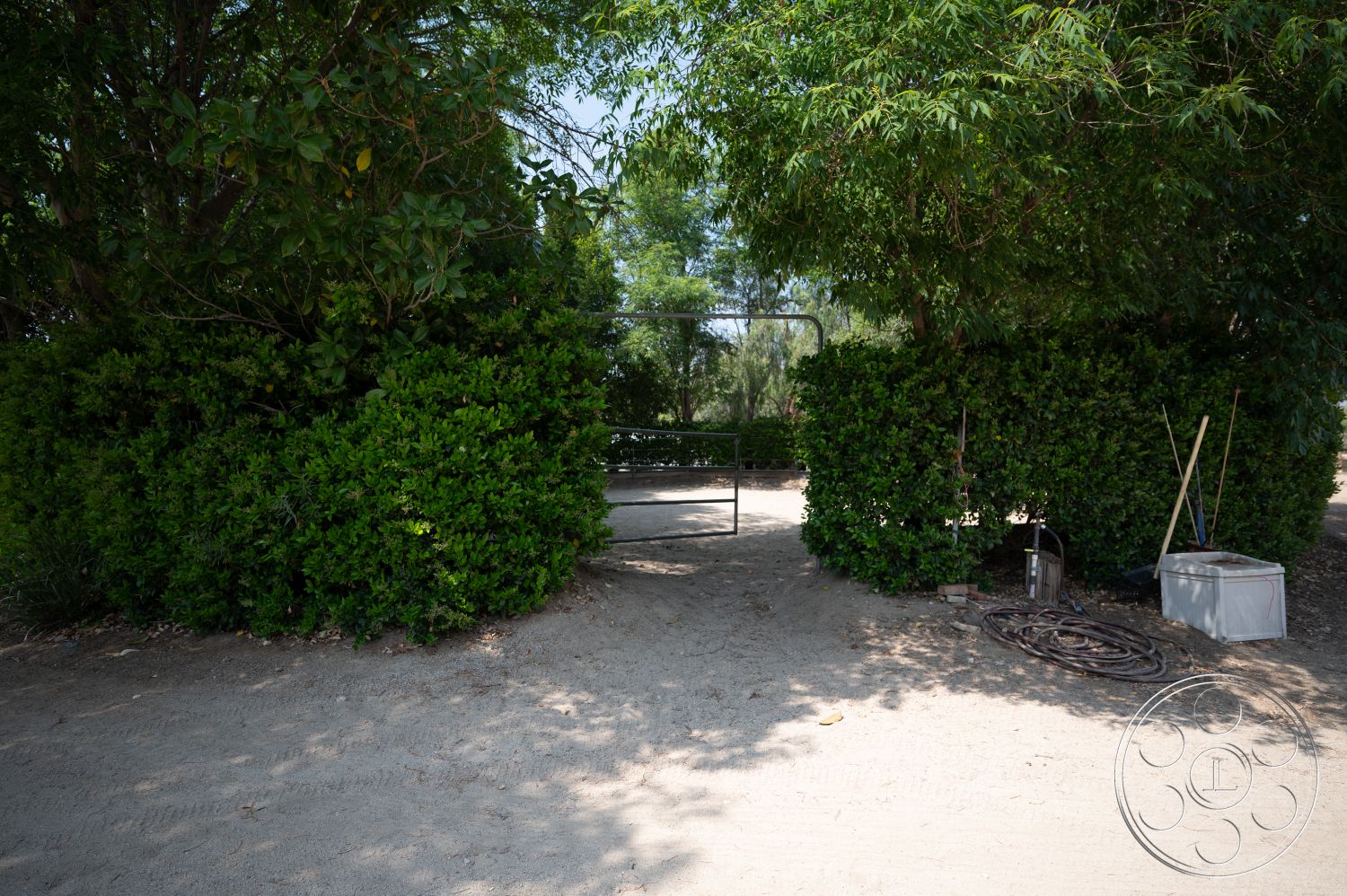Ranch 6 - exterior, surrounding trees, gravel pathway, lush green hedges, dirt ground, gated entry, open space setting