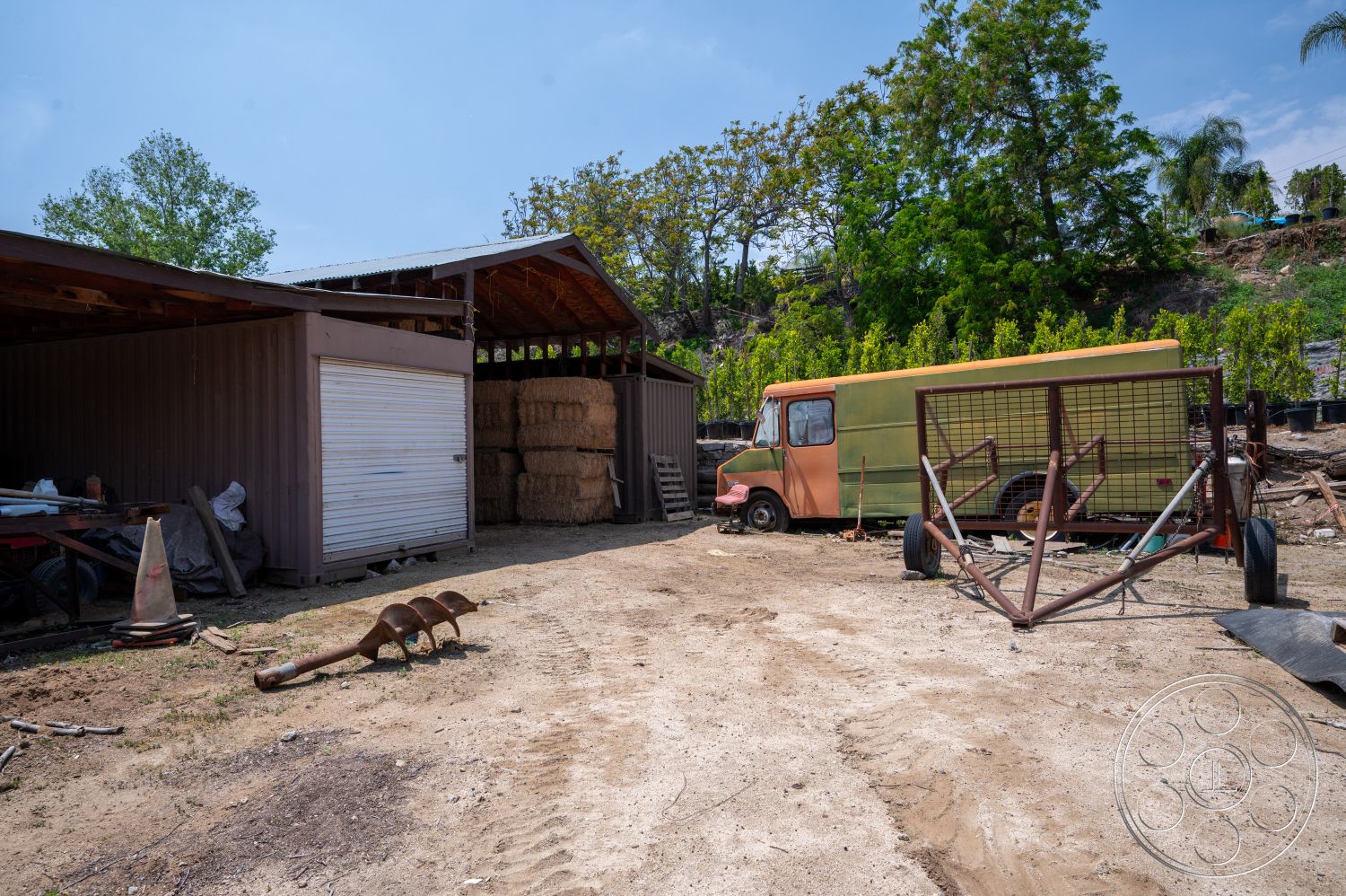 Ranch 6 - gravel driveway, landscaped with trees, interior storage space, metal storage shed, rustic farm setting, dirt yard area, hay bales, wooden beam roof structure, exposed metal siding, vintage delivery truck, rusted metal gate, outdoor work area, commercial agriculture environment