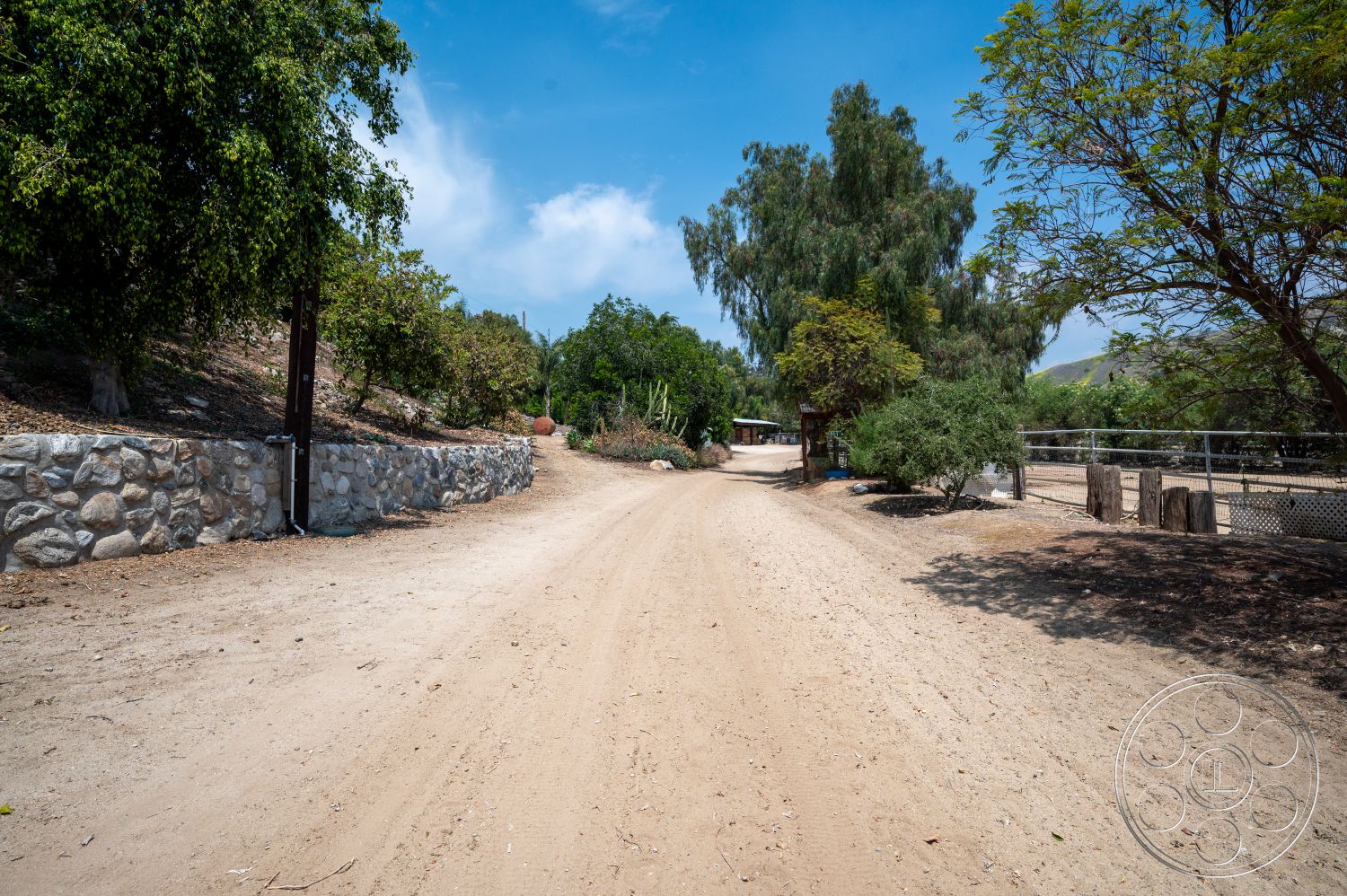 Ranch 6 - exterior, dirt path, ornamental plants, gravel driveway, deciduous trees, stone retaining wall, dry landscape, hilly terrain, fenced pasture, open countryside setting