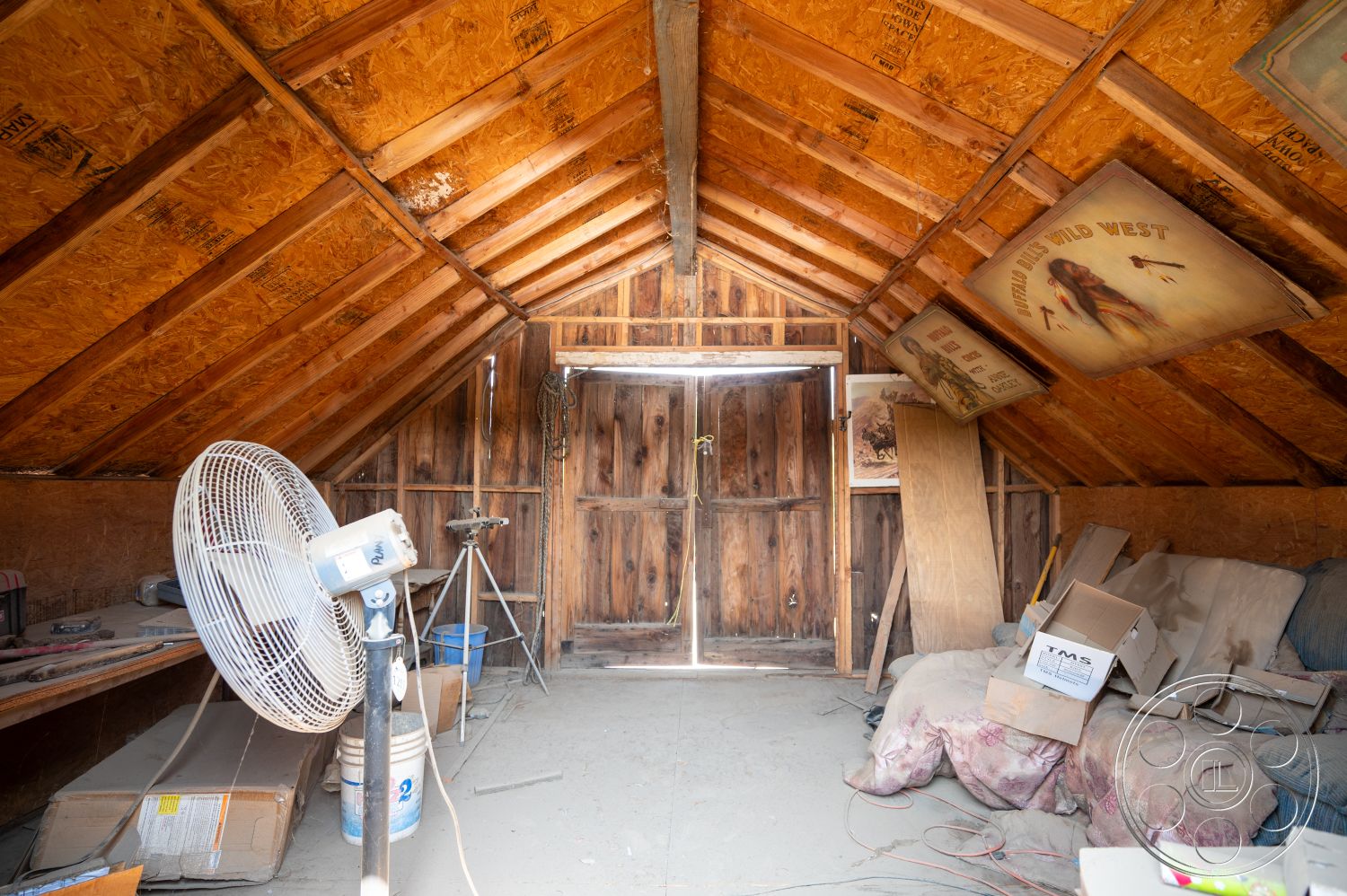 Ranch 6 - natural light, concrete floor, wooden door, sloped roof, vintage decor, rustic interior, plywood wall paneling, exposed wood rafters, unfinished attic space, wood support beams, textured wood accents