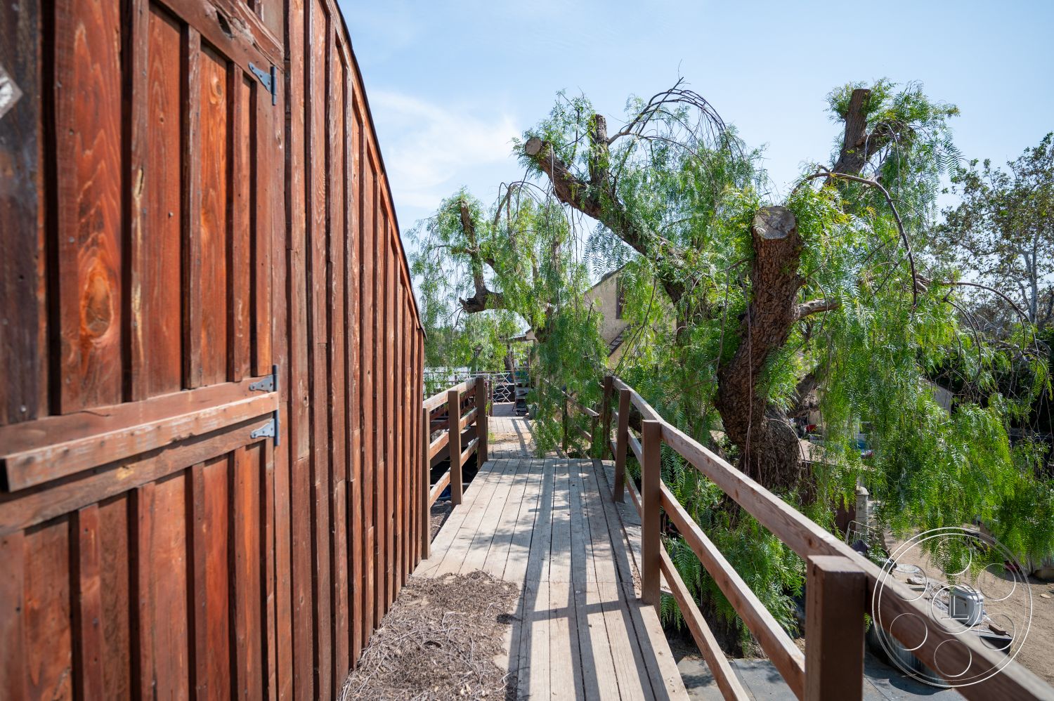 Ranch 6 - exterior, landscaped garden, native trees, natural setting, wooden fence, weathered wood deck, stained wood siding, deck railing, asphalt walkway, dry soil