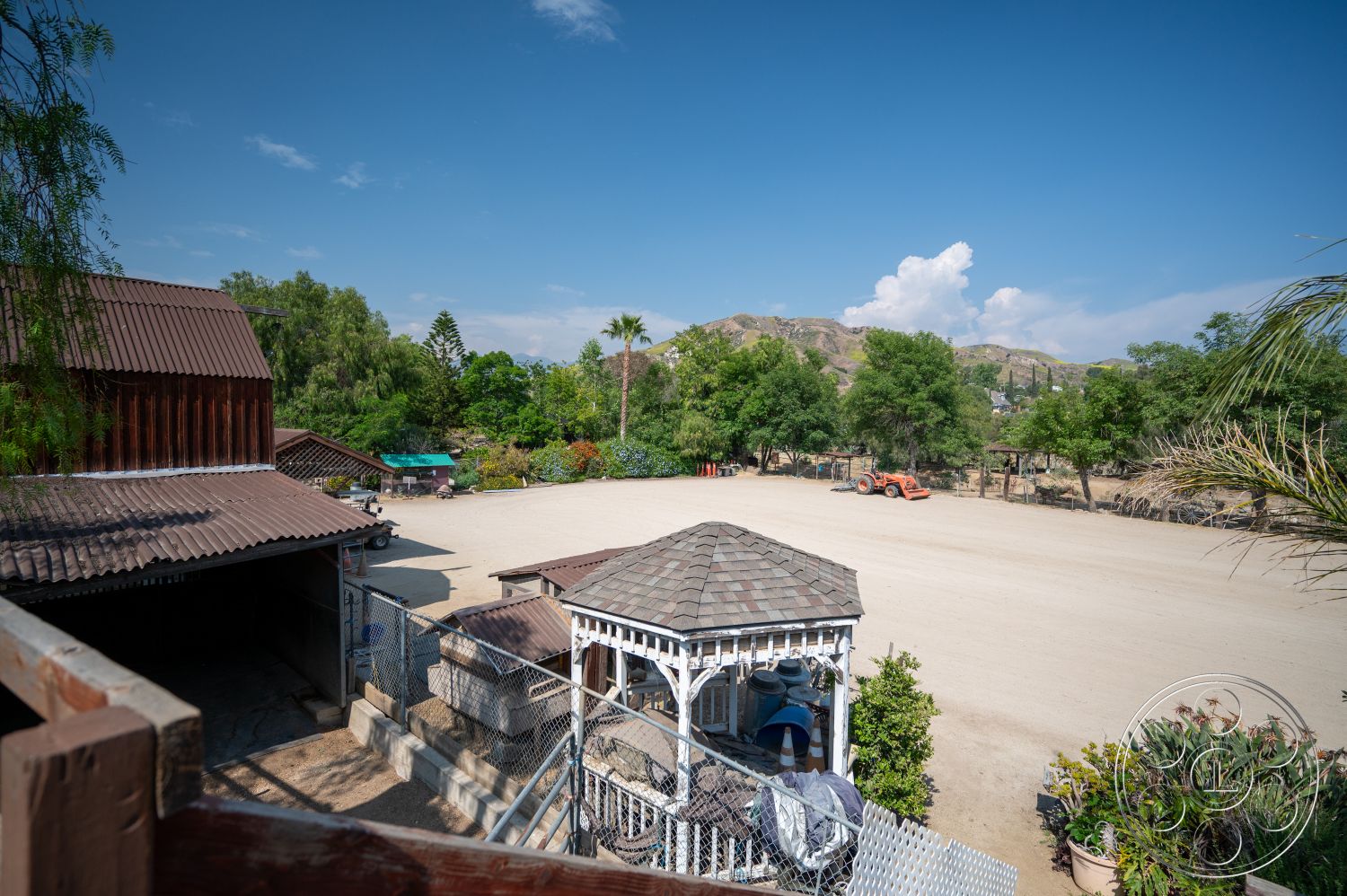 Ranch 6 - exterior, green foliage, mountain view, gravel driveway, metal roof, wooden gazebo, outdoor environment, wooden fencing, landscape vegetation, wood barn structure, shingled gazebo roof, open dirt area