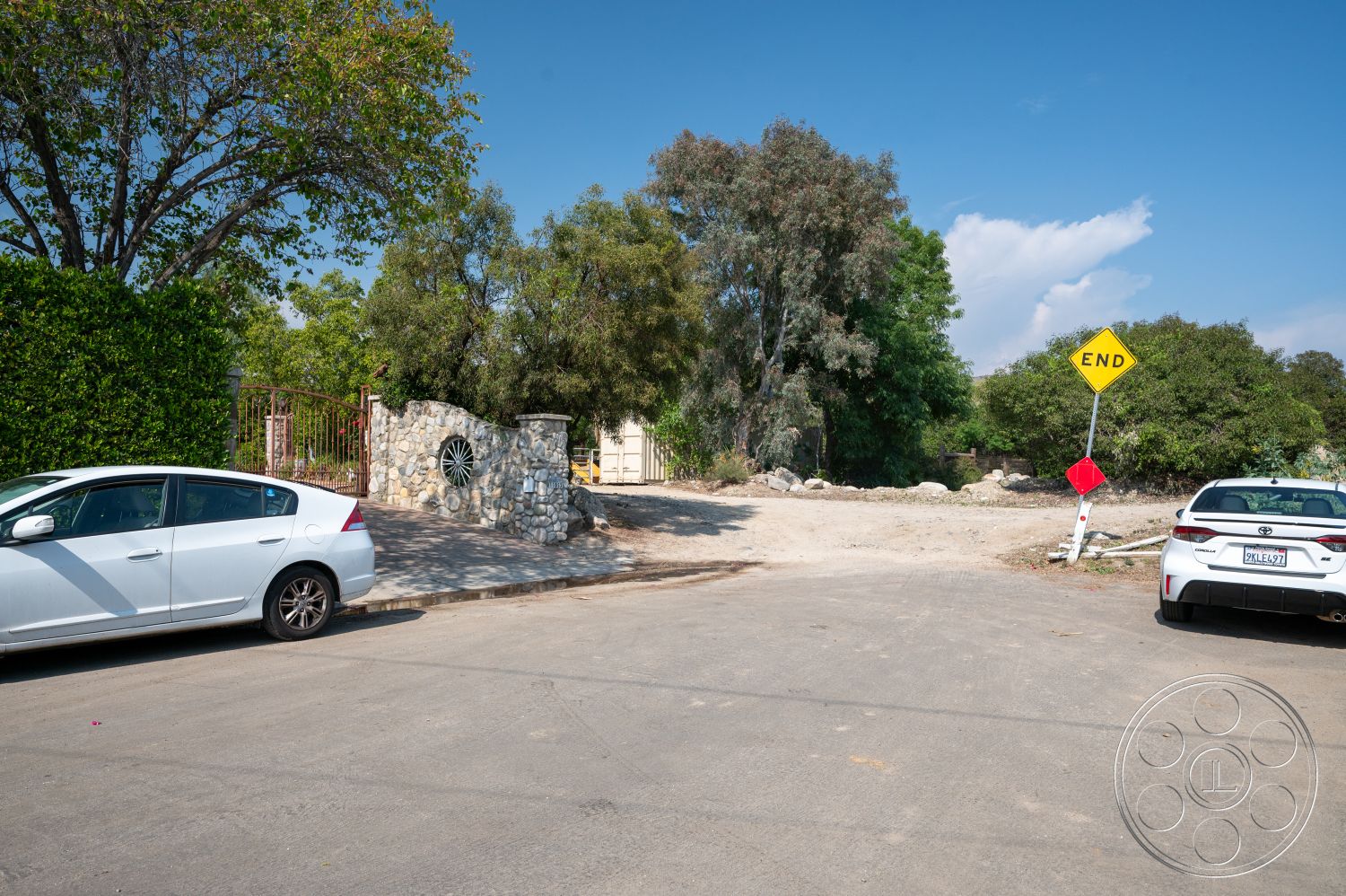 Ranch 6 - exterior, paved road, native trees, clear blue sky, lush green hedges, cobblestone pathway, urban neighborhood, stone gate entrance, end of road signage