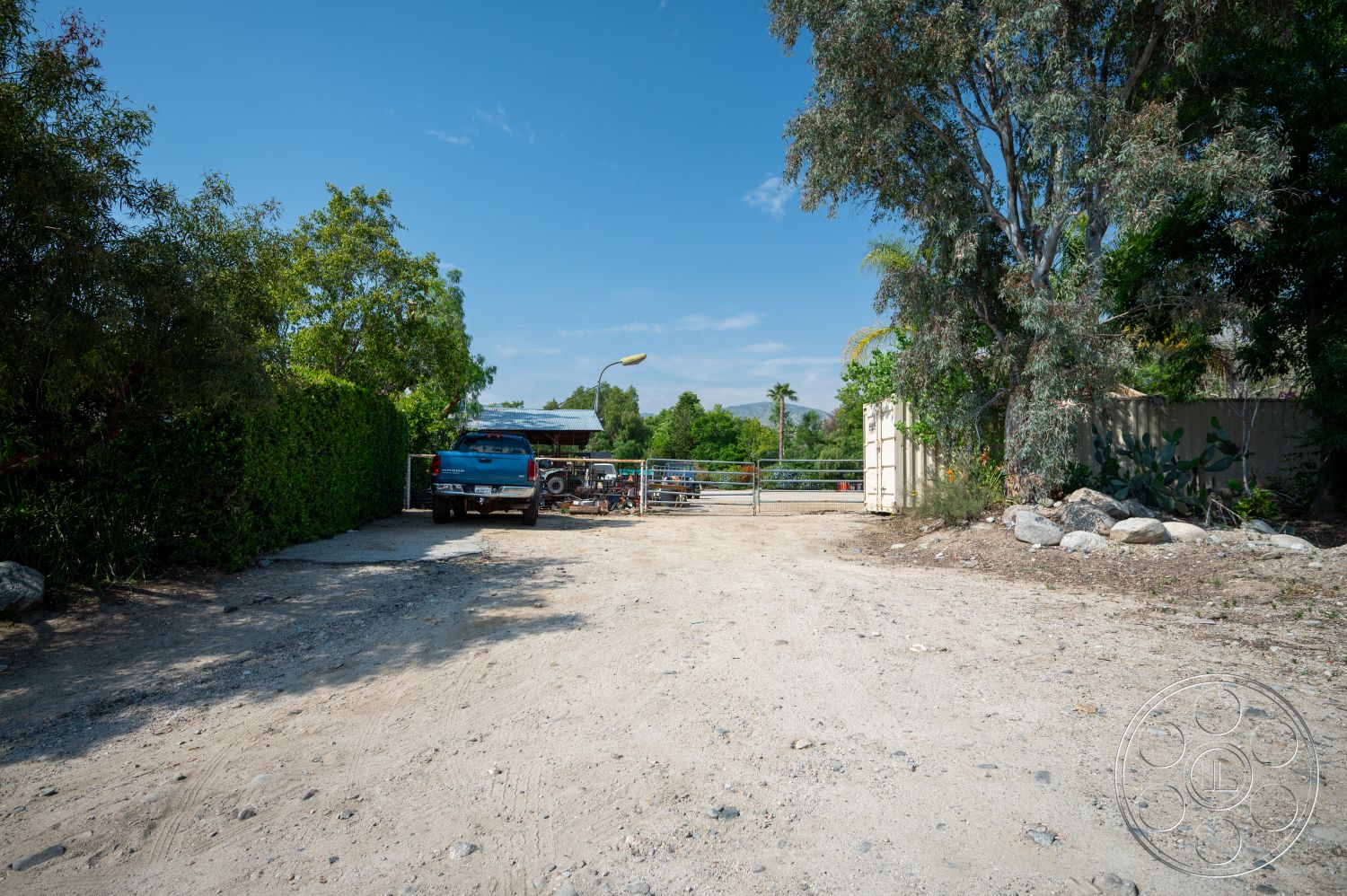Ranch 6 - surrounding greenery, metal gate, rural setting, gravel driveway, open sky, outdoor lighting fixture, hedge fence, dirt and gravel surface, exterior setting