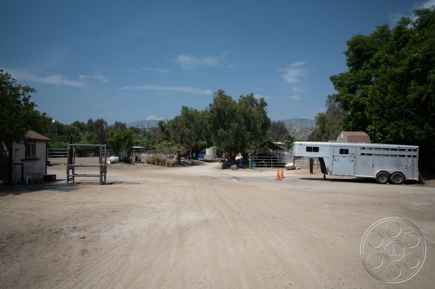 Ranch 6 - mountain view, wooden fence, outdoor structure, dirt driveway, rural environment, agricultural setting, tree-lined property, metal horse trailer, open pasture area, farm buildings