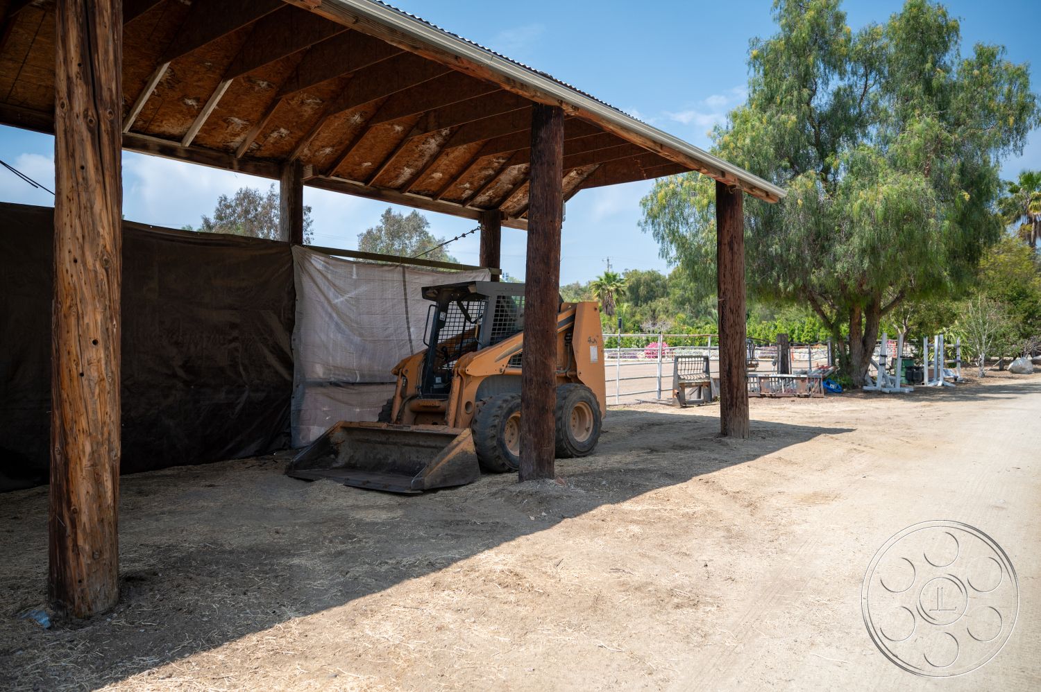 Ranch 6 - exterior, surrounding greenery, agricultural setting, wooden support beams, metal roof structure, earthy soil ground, heavy machinery equipment, open-air barn design, textured canvas wall, rustic construction