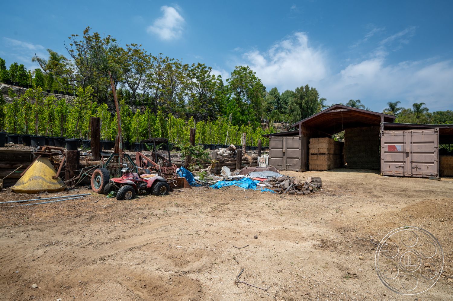 Ranch 6 - surrounding greenery, dirt floor, weathered wooden beams, farm environment, stacked hay bales, outdoor storage structure, wooden barn-style roof, black plastic plant pots, tractor with four wheels, blue tarp covering materials, flat landscape