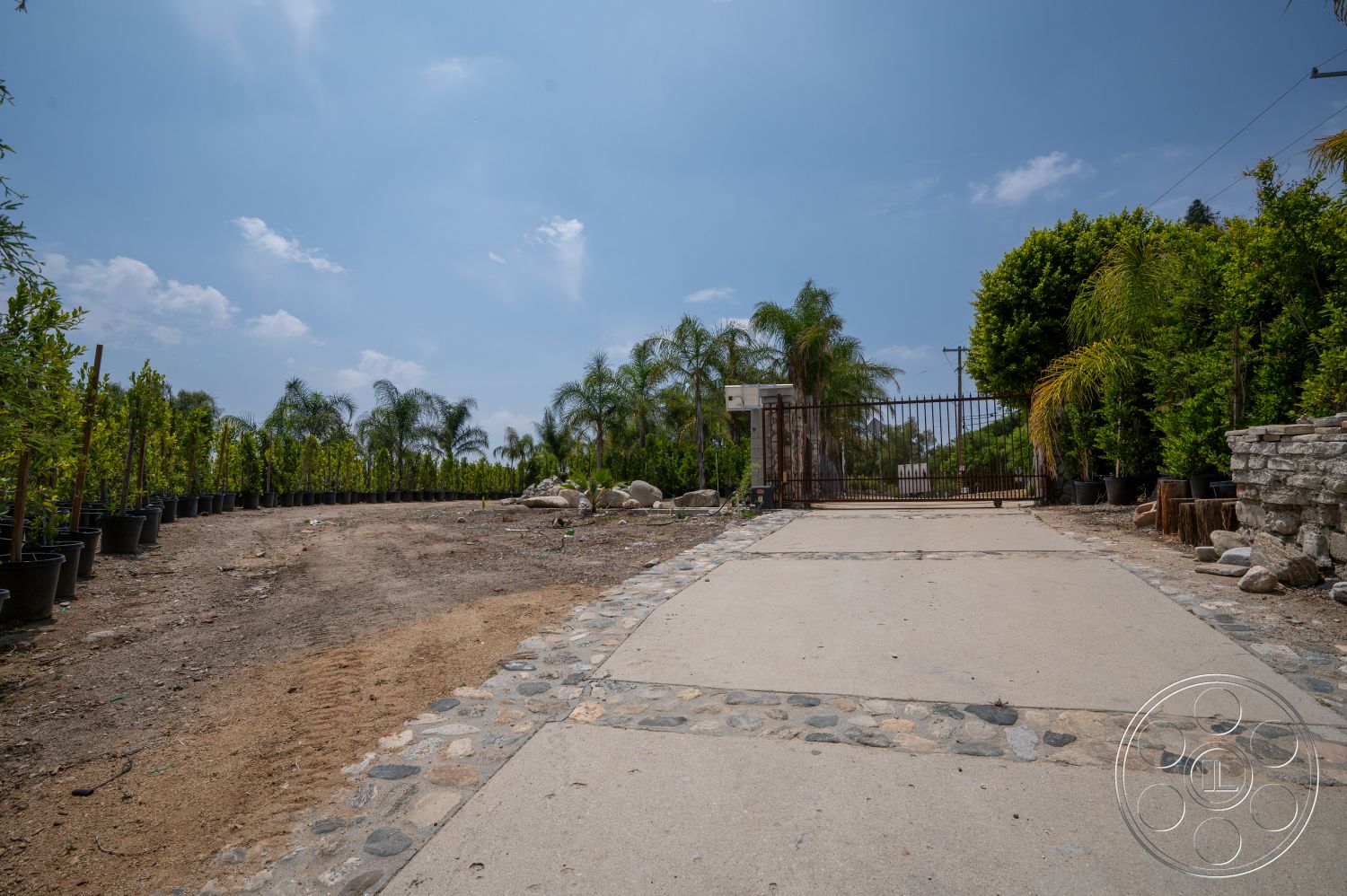 Ranch 6 - exterior, landscaped garden, tropical plants, urban setting, gated entrance, concrete driveway, gravel path, potted shrubs, paved stone border, dirt area