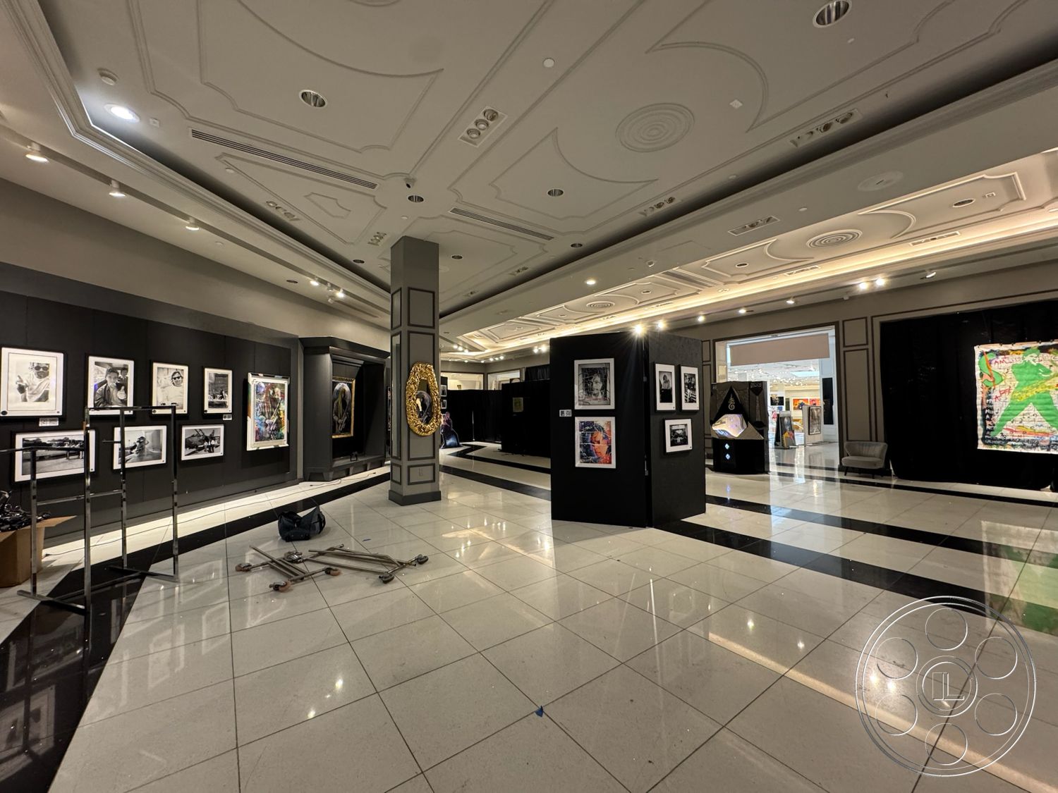 Beverly Gallery - polished tile flooring, black accent walls, recessed lighting fixtures, framed artwork on display, interior gallery space, geometric ceiling moldings, elegant wall-mounted mirrors, square column details, striped tile patterns, exhibition area with display stands