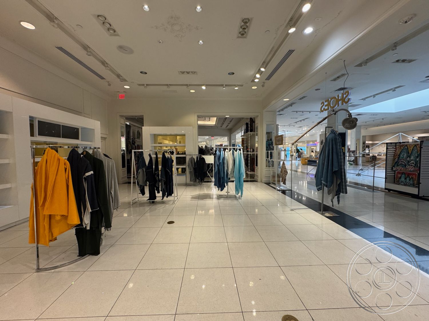 Beverly Gallery - open floor plan, clothing racks, modern minimalist design, bright recessed lighting, white painted walls, interior retail space, fashion display area, polished porcelain tile flooring, glass display racks, elegant ceiling details