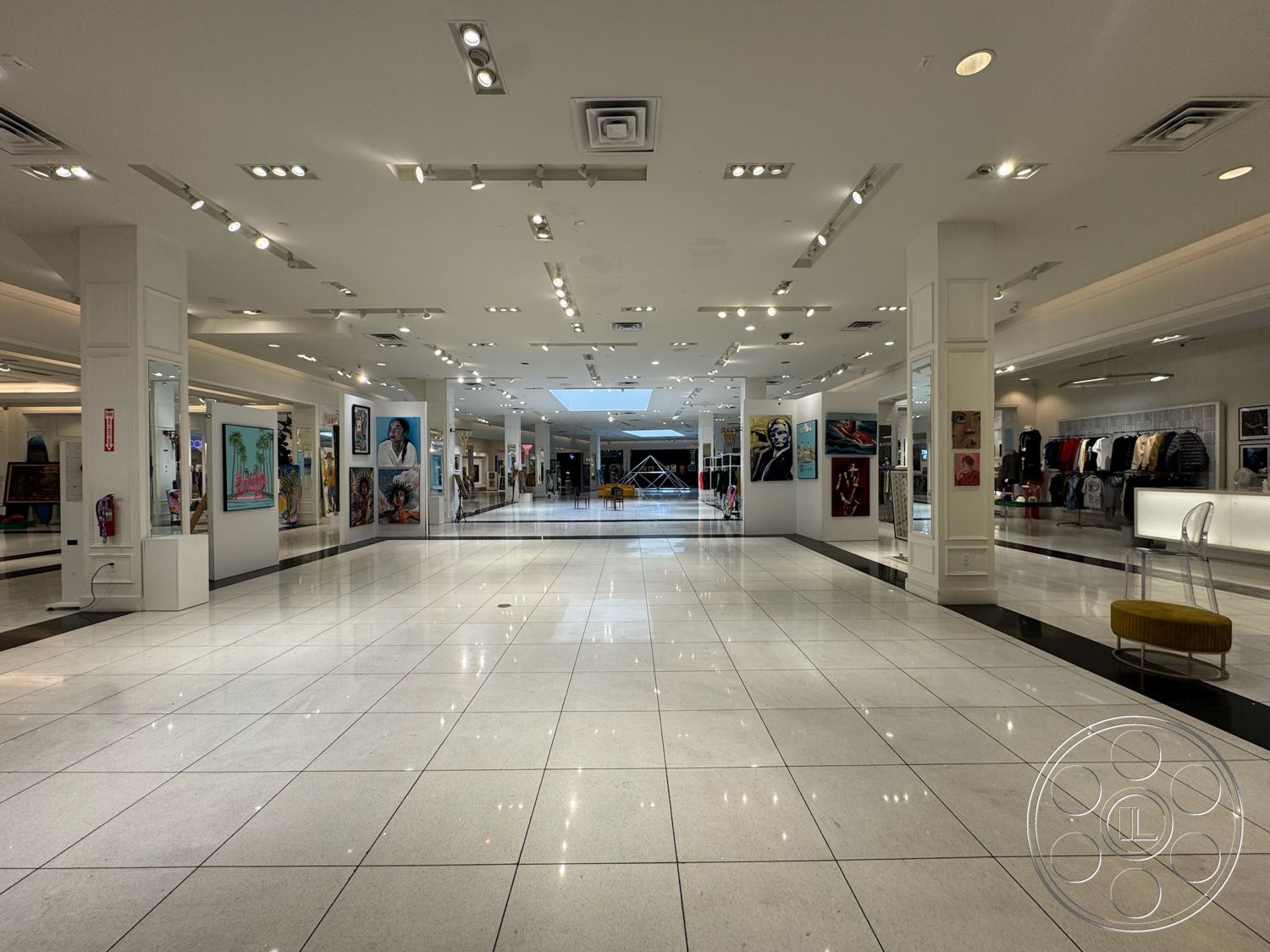 Beverly Gallery - minimalist design, contemporary furniture, polished marble flooring, open retail layout, art display walls, large skylight, grid ceiling with recessed lighting, white panel walls, modern display fixtures, black accent flooring