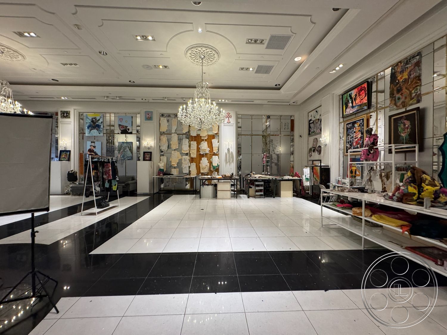 Beverly Gallery - contemporary style, neutral wall colors, open layout, polished tile flooring, brightly lit space, modern art displays, chandelier lighting fixtures, exposed ceiling design, black and white checkered tile floor, soft ceiling details, mirrored wall accents, freestanding display racks, art studio environment