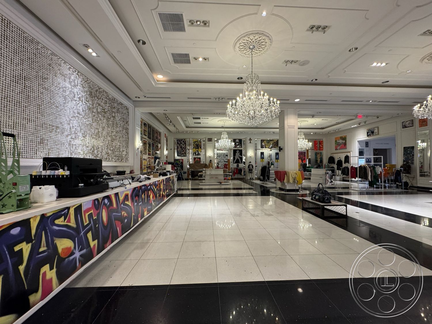 Beverly Gallery - high ceilings, open layout, artistic wall decor, polished marble flooring, contemporary aesthetic, glass display cases, exposed brick accent wall, modern retail environment, graffiti art mural, white decorative plaster ceiling, chandelier light fixtures, stylish clothing displays, striped black and white floor pattern