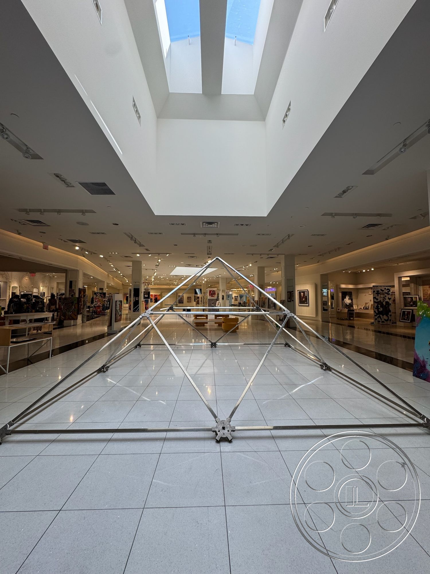 Beverly Gallery - open floor plan, high ceiling, suspended ceiling, glossy tile flooring, white painted walls, minimalist architectural design, skylight ceiling, track lighting fixtures, modern art display area, geometric steel structure, spacious commercial space