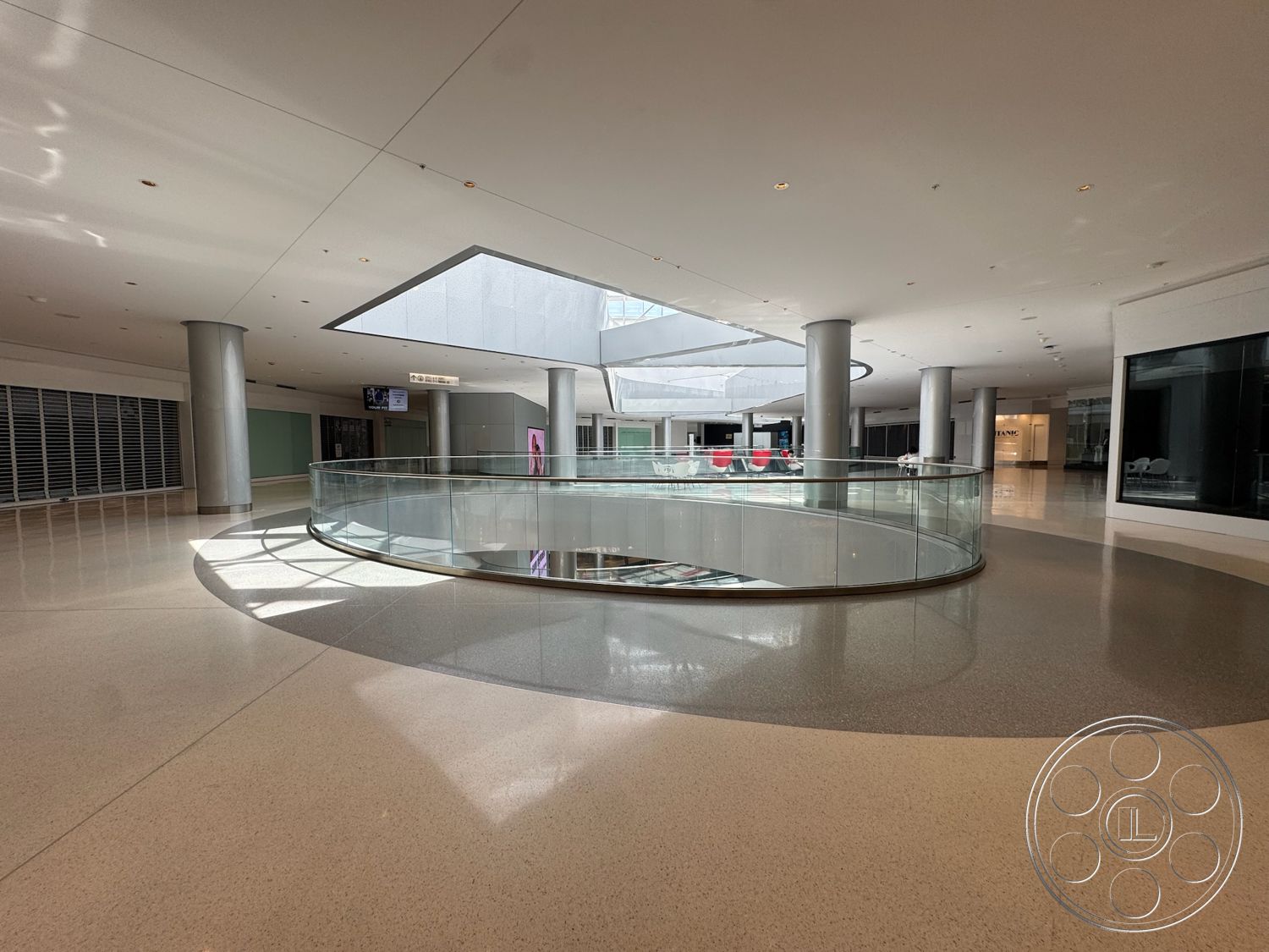Beverly Gallery - polished concrete flooring, floor-to-ceiling windows, modern architectural style, contemporary lighting fixtures, minimalist interior design, open floor plan layout, curved glass railing, natural light features, exposed column structures, commercial space configuration, reflective ceiling panels, central atrium area