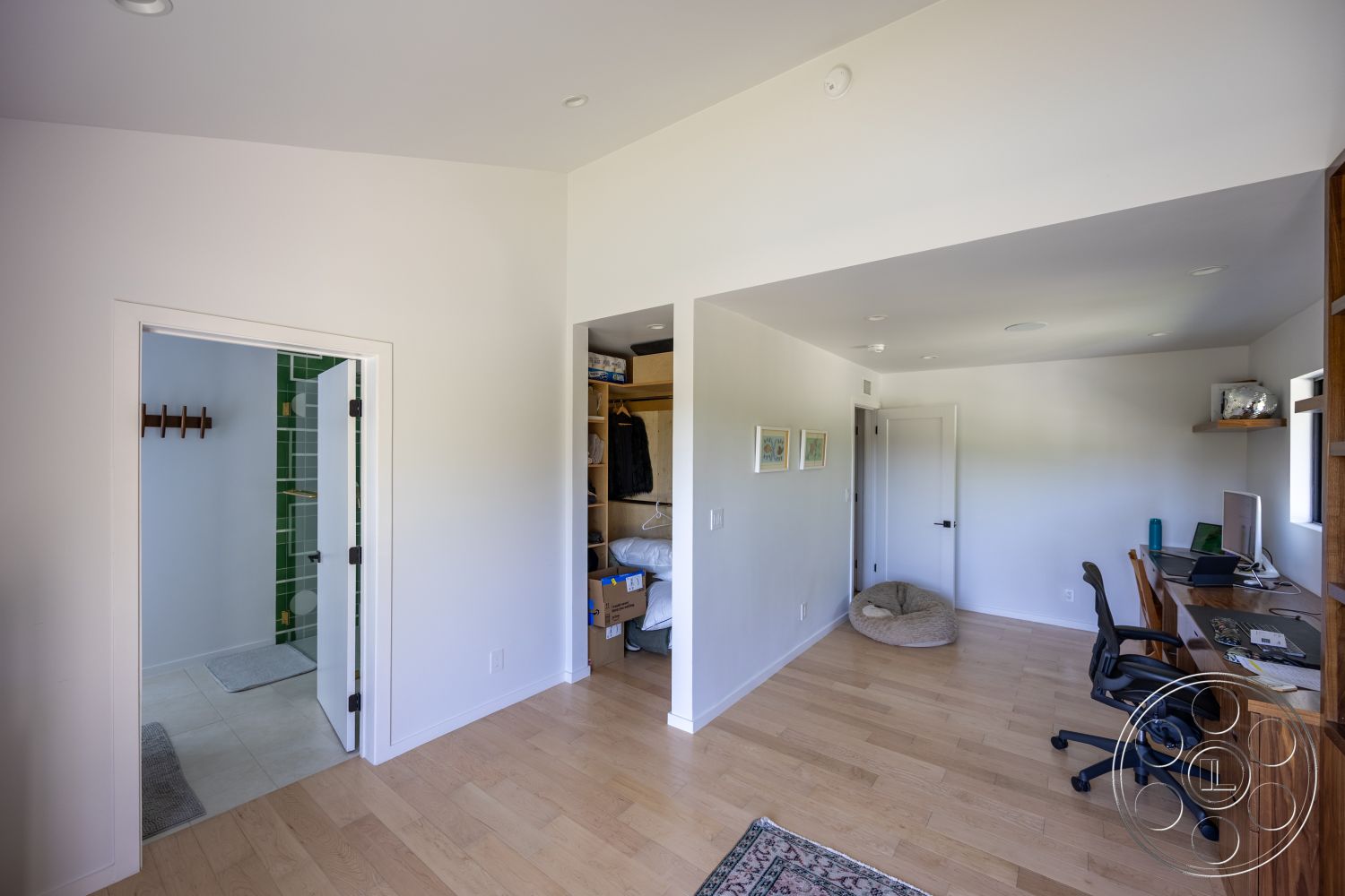 Modern 390 - hardwood flooring, textured area rug, open floor plan, light wood desk, bean bag chair, white painted walls, modern office space, flush mount ceiling lights, built-in storage shelves, glass office window