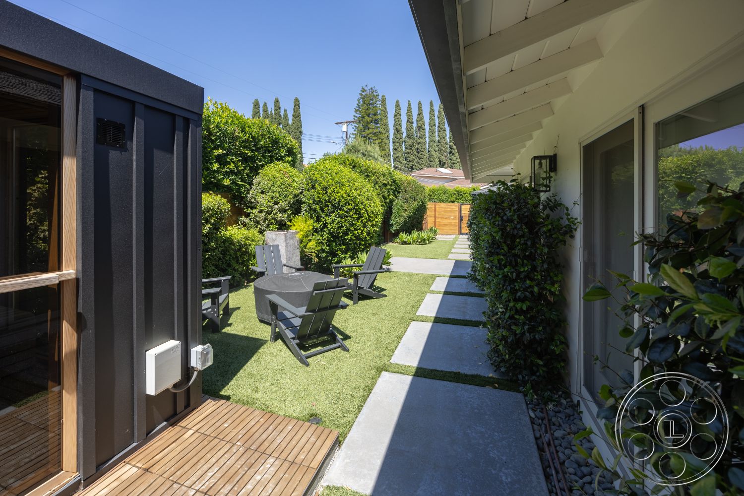 Modern 390 - exterior, horizontal wooden fence, modern outdoor seating, concrete stepping stones, wood deck flooring, decorative stone border, artificial grass lawn, landscape vegetation, flat concrete path, fiber cement siding, metal garden shed, glazed glass doors