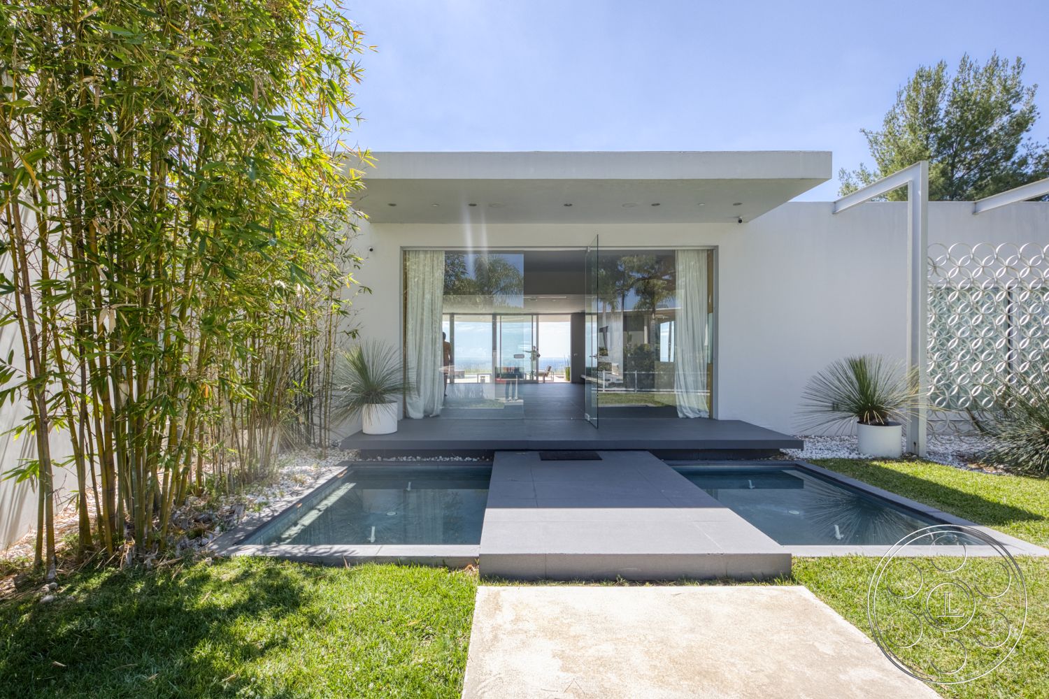 Modern 525 - exterior, white stucco walls, flat roof, sliding glass doors, concrete pathway, green lawn, rectangular pool, glass panel fencing, bamboo landscaping, concrete pool border, minimalist architectural style, stone garden accents, floating entry steps