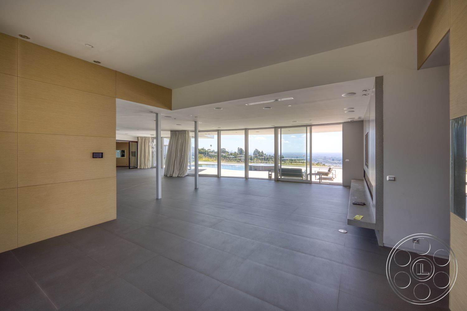 Modern 525 - open floor plan, minimalist design elements, modern architectural style, large floor-to-ceiling windows, smooth plywood wall paneling, dark porcelain tile flooring, concrete fireplace facade, natural light infused space, views of the outdoor pool area