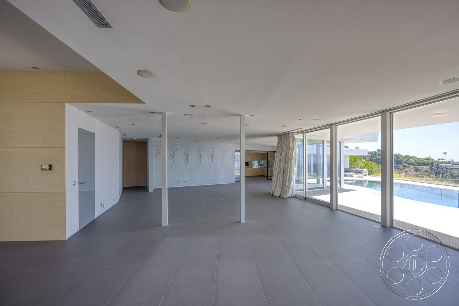Modern 525 - neutral color palette, natural light, minimalist design, sliding glass doors, modern aesthetic, floor-to-ceiling windows, open-concept living space, outdoor pool view, white painted walls, exposed steel columns, wood panel accent wall, light gray tile flooring