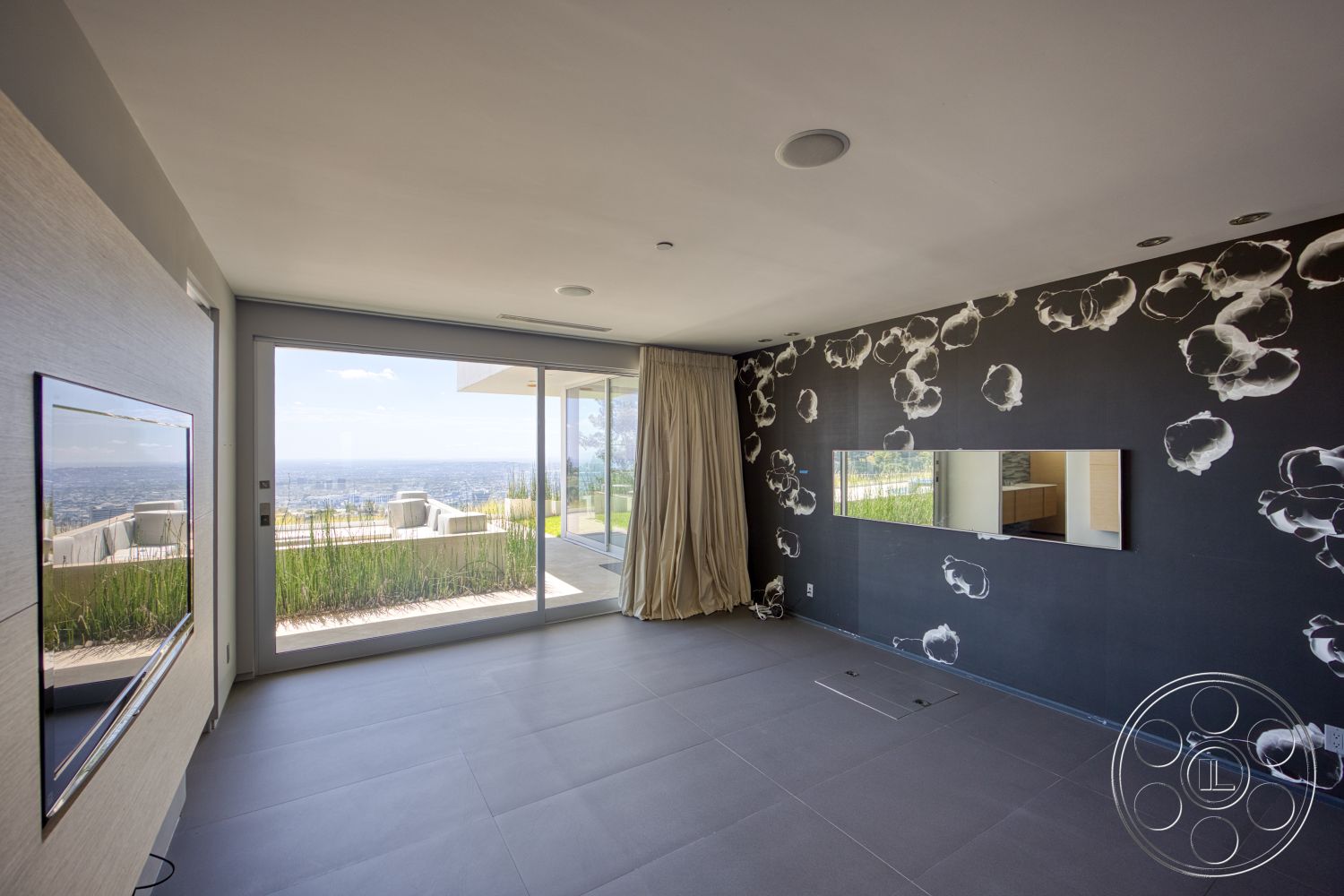Modern 525 - open floor plan, modern design elements, sliding glass doors, city skyline view, large floor-to-ceiling windows, textured plaster walls with floral pattern, neutral tiled flooring, minimalist television wall mount, curtains in beige fabric